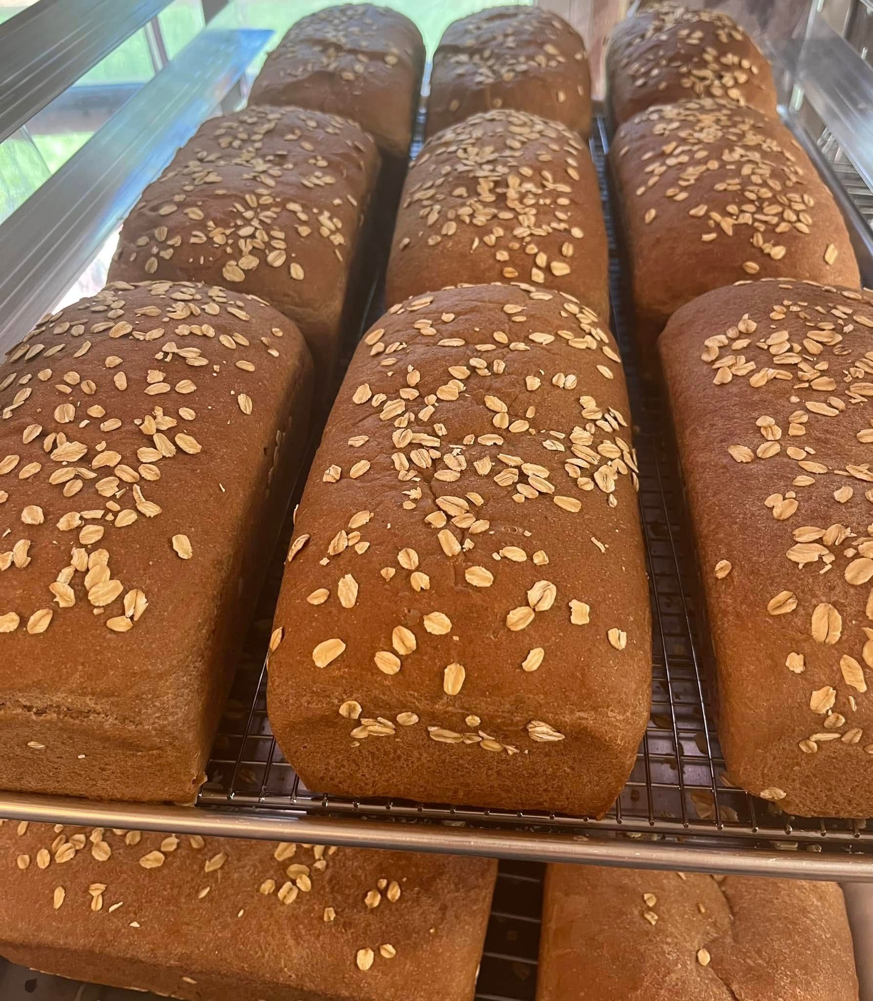 Loaves of brown bread topped with oats, cooling on a wire rack. Base Camp Bakery Gunnison, Colorado https://share.google/AgqUzUKNzsb0ThlP5, https://www.facebook.com/BaseCampBakery1, https://www.instagram.com/basecampbakery_81230