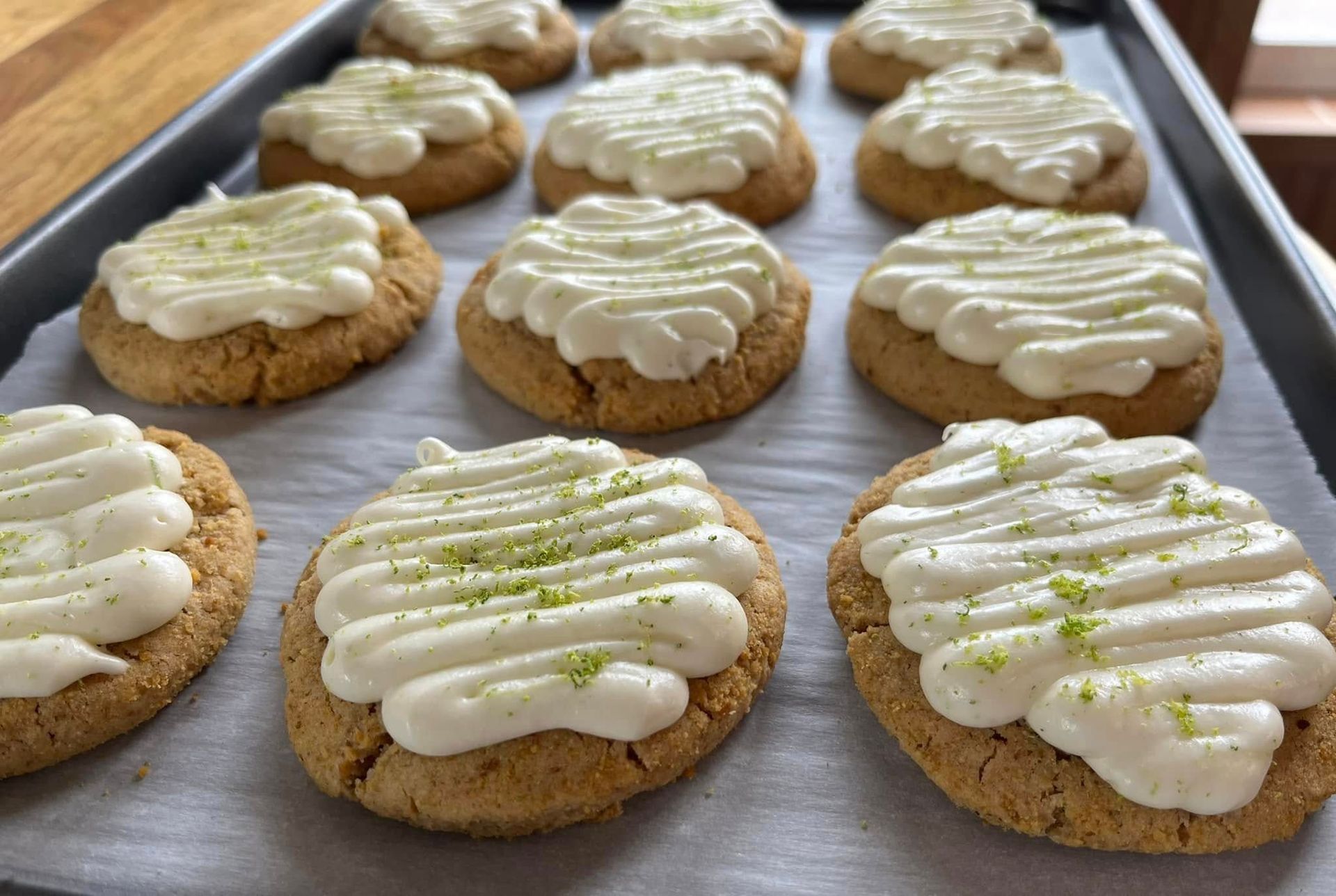 Cookies with white frosting and lime zest on a baking sheet. Base Camp Bakery Gunnison, Colorado https://share.google/AgqUzUKNzsb0ThlP5, https://www.facebook.com/BaseCampBakery1, https://www.instagram.com/basecampbakery_81230