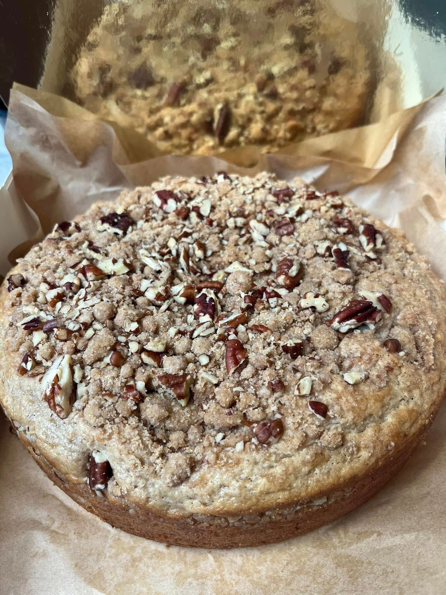 Coffee cake with pecan crumble topping on parchment paper. Base Camp Bakery Gunnison, Colorado https://share.google/AgqUzUKNzsb0ThlP5, https://www.facebook.com/BaseCampBakery1, https://www.instagram.com/basecampbakery_81230