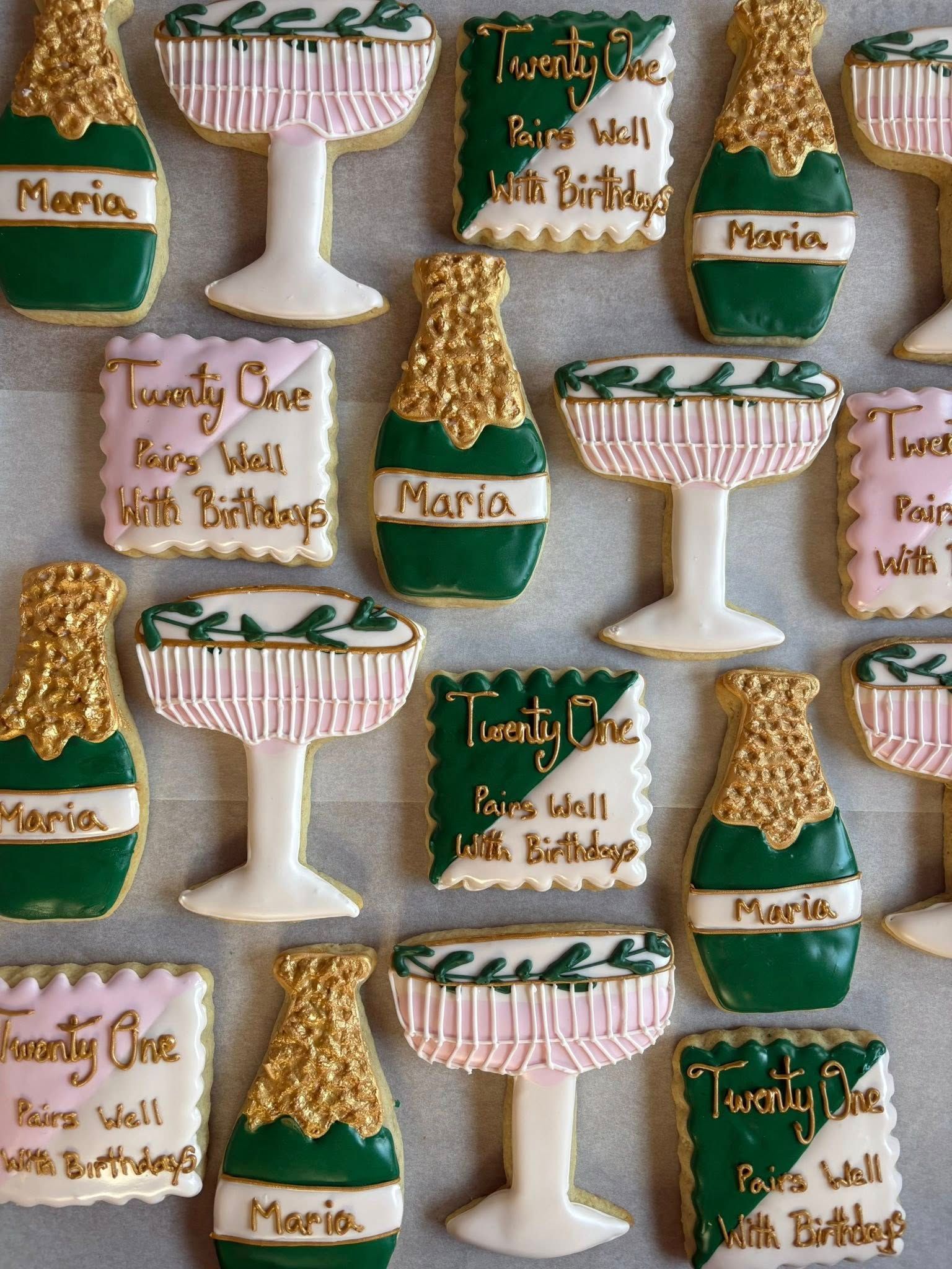 Cookies decorated as champagne bottles, glasses, and square treats, in green, gold, and pink colors. Base Camp Bakery Gunnison, Colorado https://share.google/AgqUzUKNzsb0ThlP5, https://www.facebook.com/BaseCampBakery1, https://www.instagram.com/basecampbakery_81230