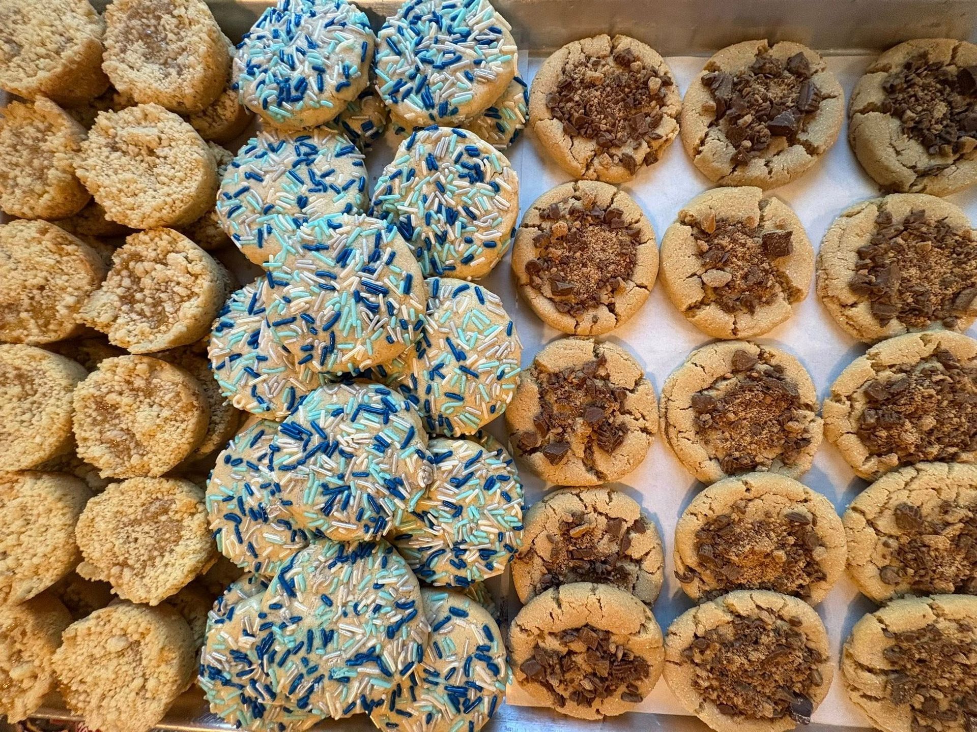 Cookies on a tray: three rows, varieties include sprinkles and crumble topping. Base Camp Bakery Gunnison, Colorado https://share.google/AgqUzUKNzsb0ThlP5, https://www.facebook.com/BaseCampBakery1, https://www.instagram.com/basecampbakery_81230