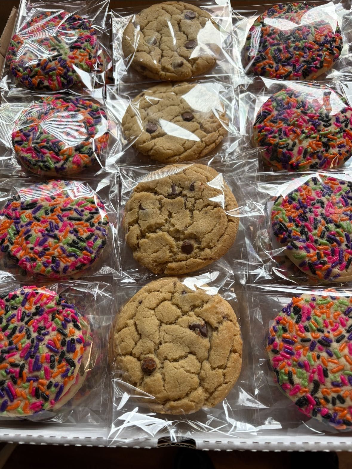 Cookies in clear plastic wrappers arranged in a box. Some are sprinkled, others have chocolate chips. Base Camp Bakery Gunnison, Colorado https://share.google/AgqUzUKNzsb0ThlP5, https://www.facebook.com/BaseCampBakery1, https://www.instagram.com/basecampbakery_81230