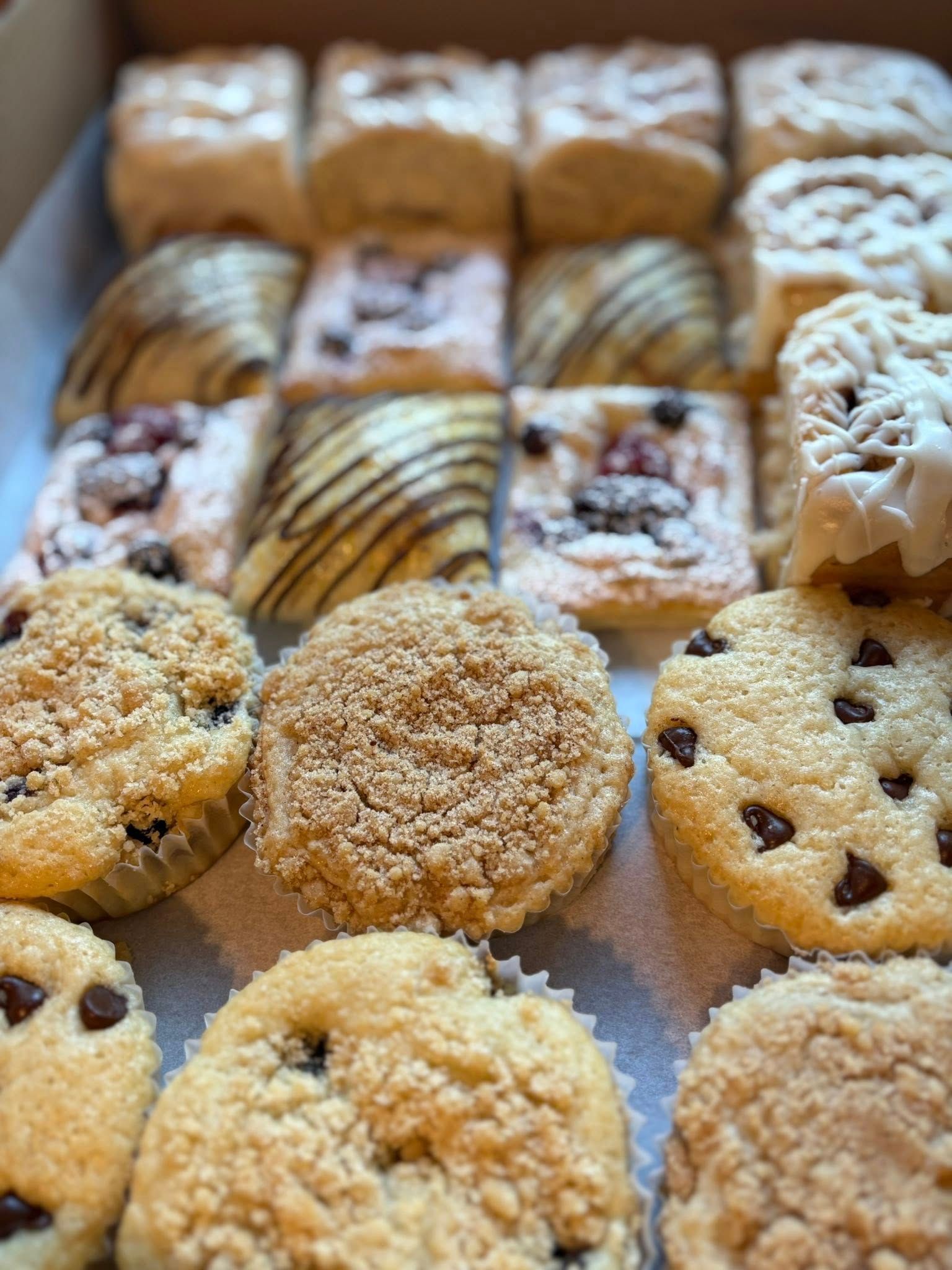 Box of various pastries: muffins, scones, and danishes with chocolate chips and frosting. Base Camp Bakery Gunnison, Colorado https://share.google/AgqUzUKNzsb0ThlP5, https://www.facebook.com/BaseCampBakery1, https://www.instagram.com/basecampbakery_81230