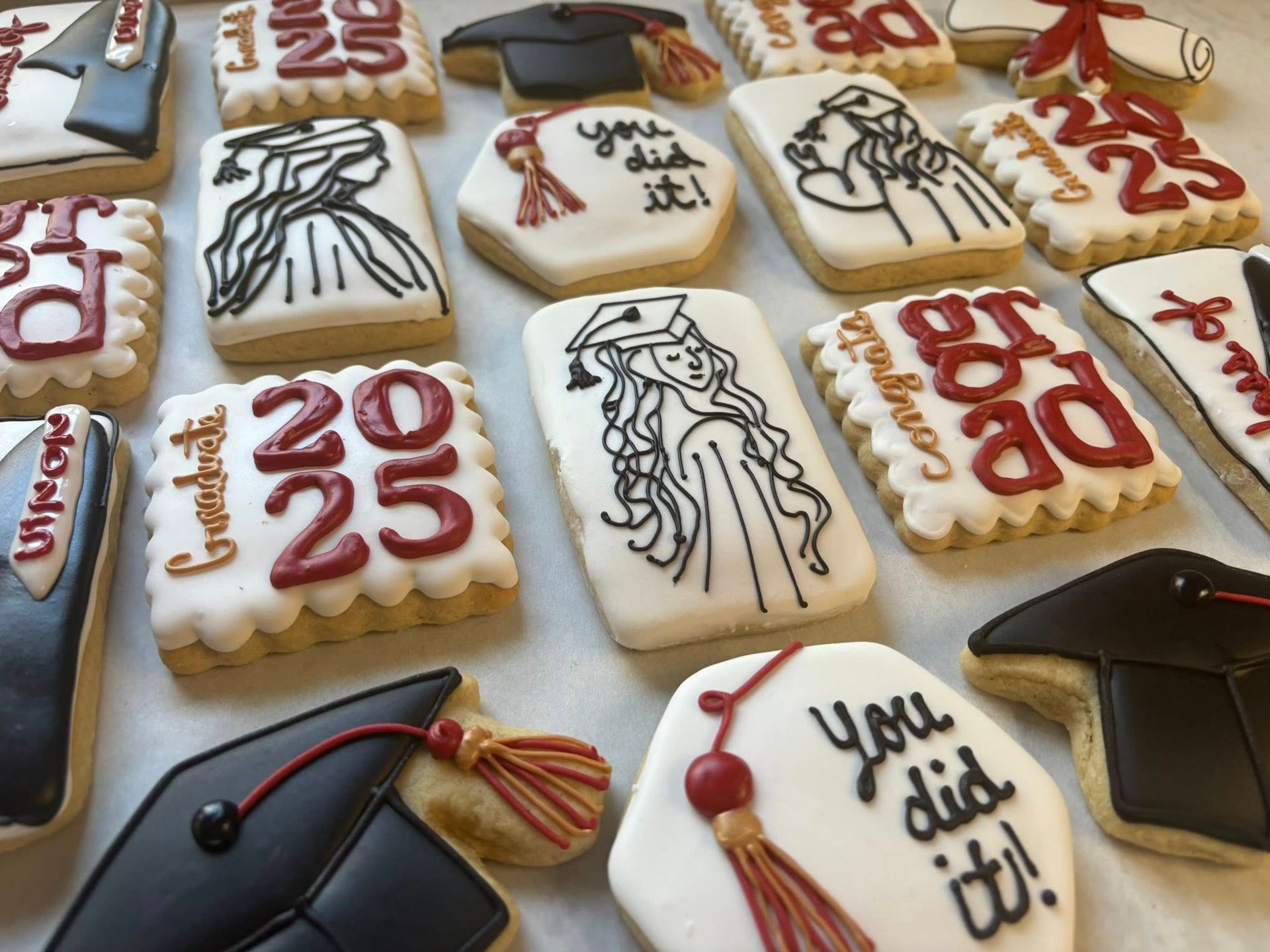 Graduation-themed decorated cookies, featuring mortarboards, gowns. Base Camp Bakery Gunnison, Colorado https://share.google/AgqUzUKNzsb0ThlP5, https://www.facebook.com/BaseCampBakery1, https://www.instagram.com/basecampbakery_81230