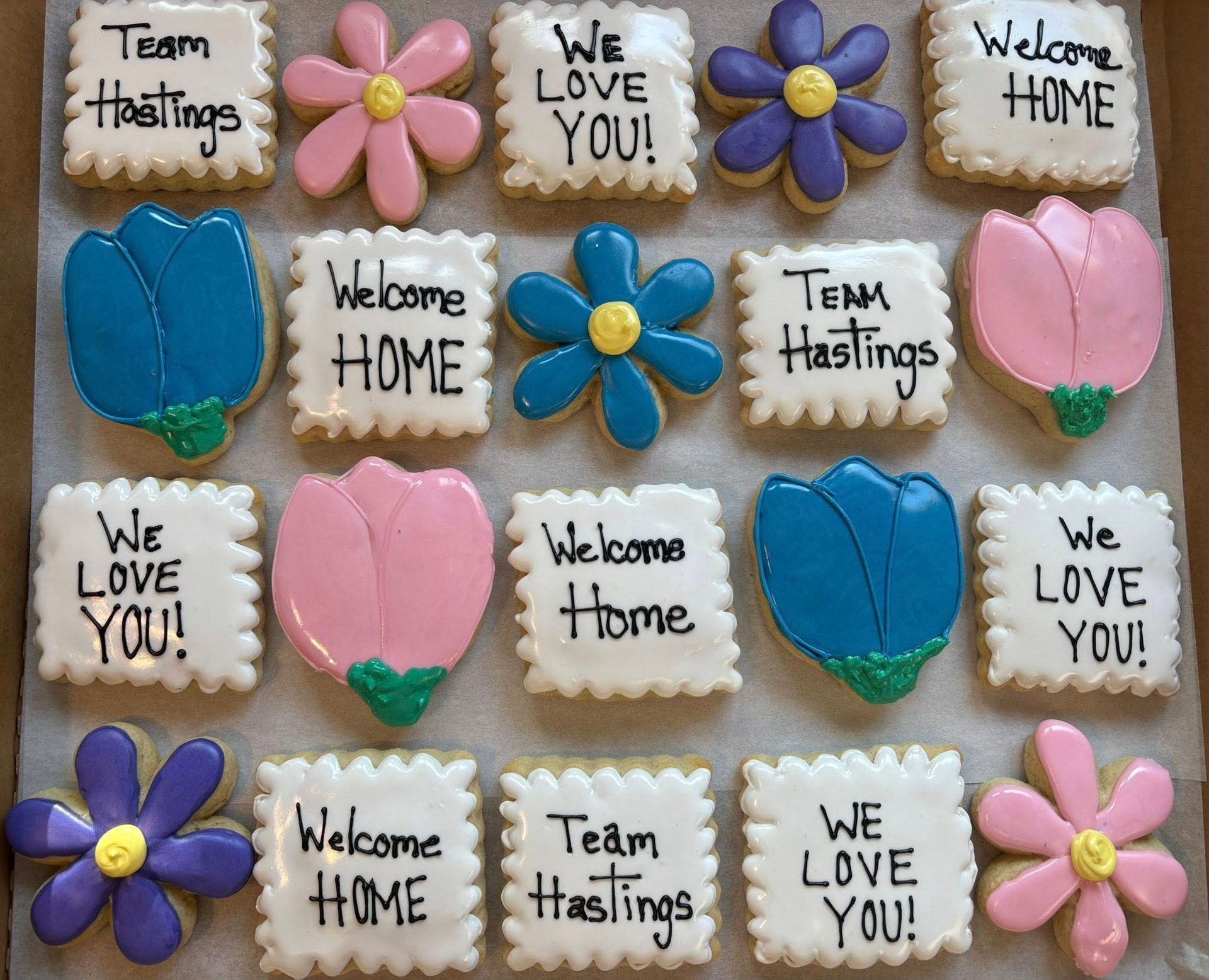 Assortment of decorated cookies in various shapes: flowers and squares. Base Camp Bakery Gunnison, Colorado https://share.google/AgqUzUKNzsb0ThlP5, https://www.facebook.com/BaseCampBakery1, https://www.instagram.com/basecampbakery_81230