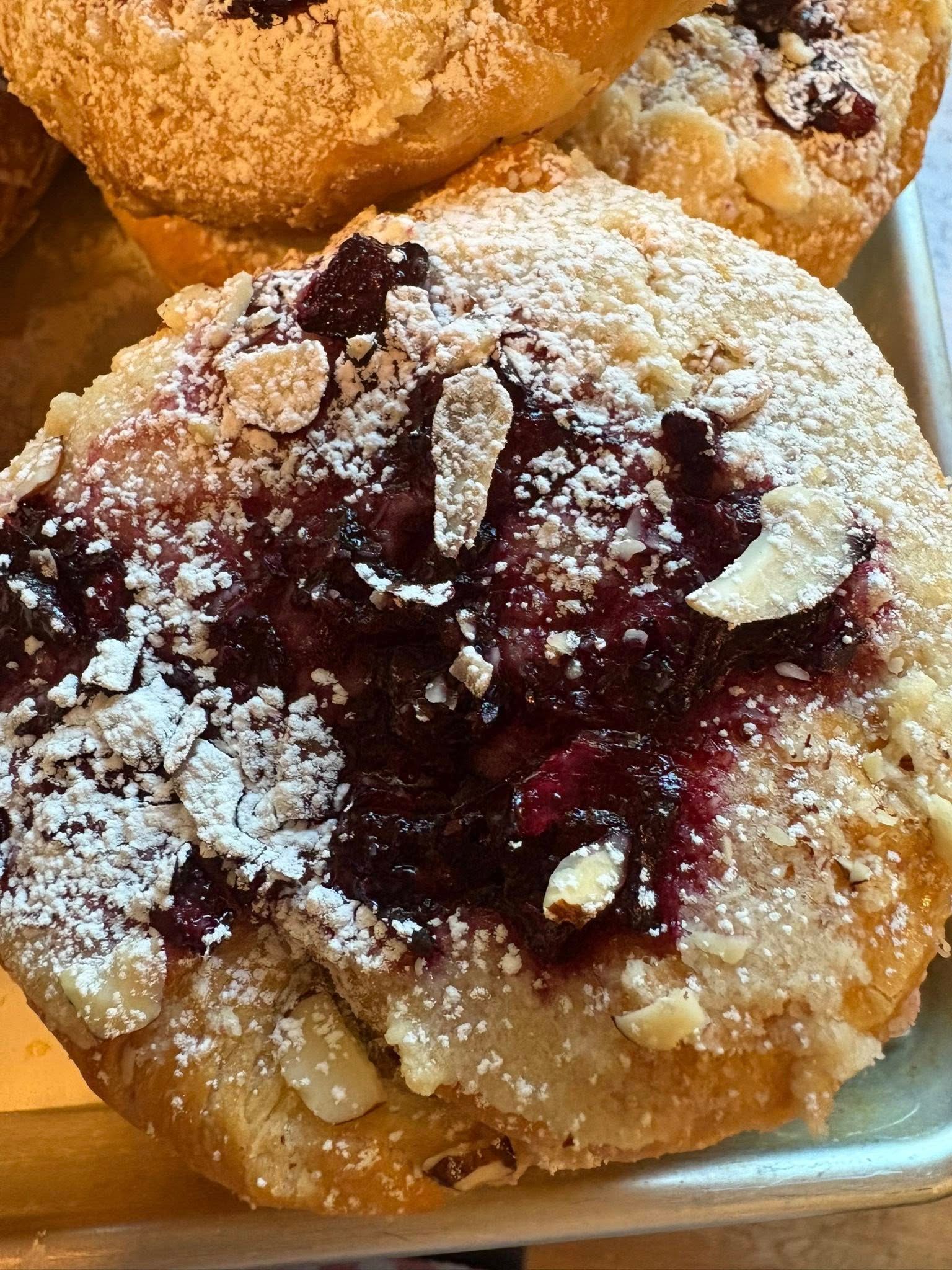 Pastry with berry filling, almond slices, and powdered sugar. Base Camp Bakery Gunnison, Colorado https://share.google/AgqUzUKNzsb0ThlP5, https://www.facebook.com/BaseCampBakery1, https://www.instagram.com/basecampbakery_81230
