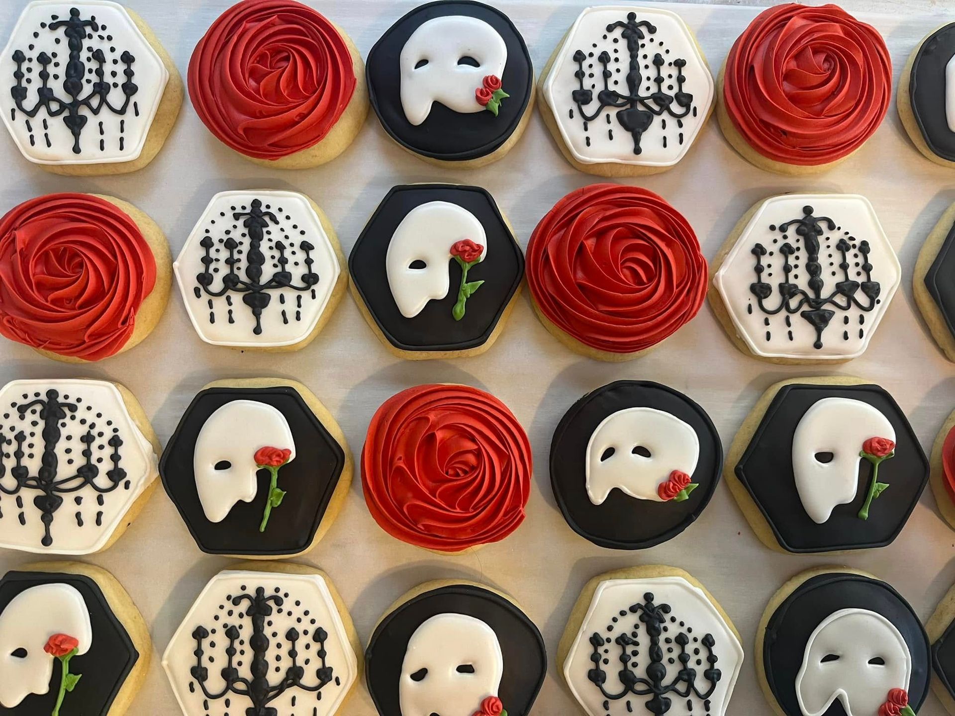 Cookies decorated with red roses, Phantom of the Opera masks, and black and white chandelier designs. Base Camp Bakery Gunnison, Colorado https://share.google/AgqUzUKNzsb0ThlP5, https://www.facebook.com/BaseCampBakery1, https://www.instagram.com/basecampbakery_81230