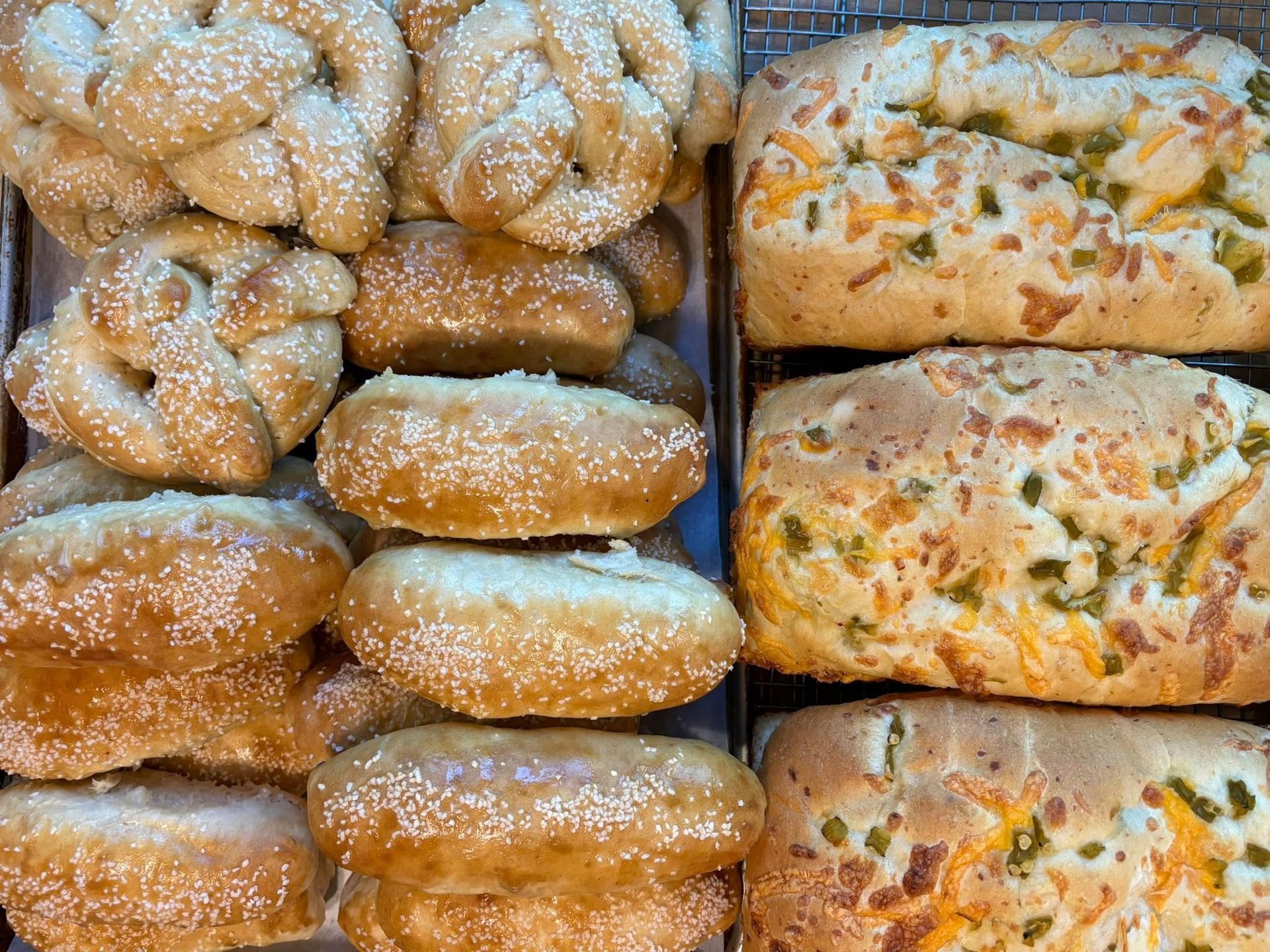 Assortment of baked goods, including pretzels and loaves with cheese and jalapeños. Base Camp Bakery Gunnison, Colorado https://share.google/AgqUzUKNzsb0ThlP5, https://www.facebook.com/BaseCampBakery1, https://www.instagram.com/basecampbakery_81230