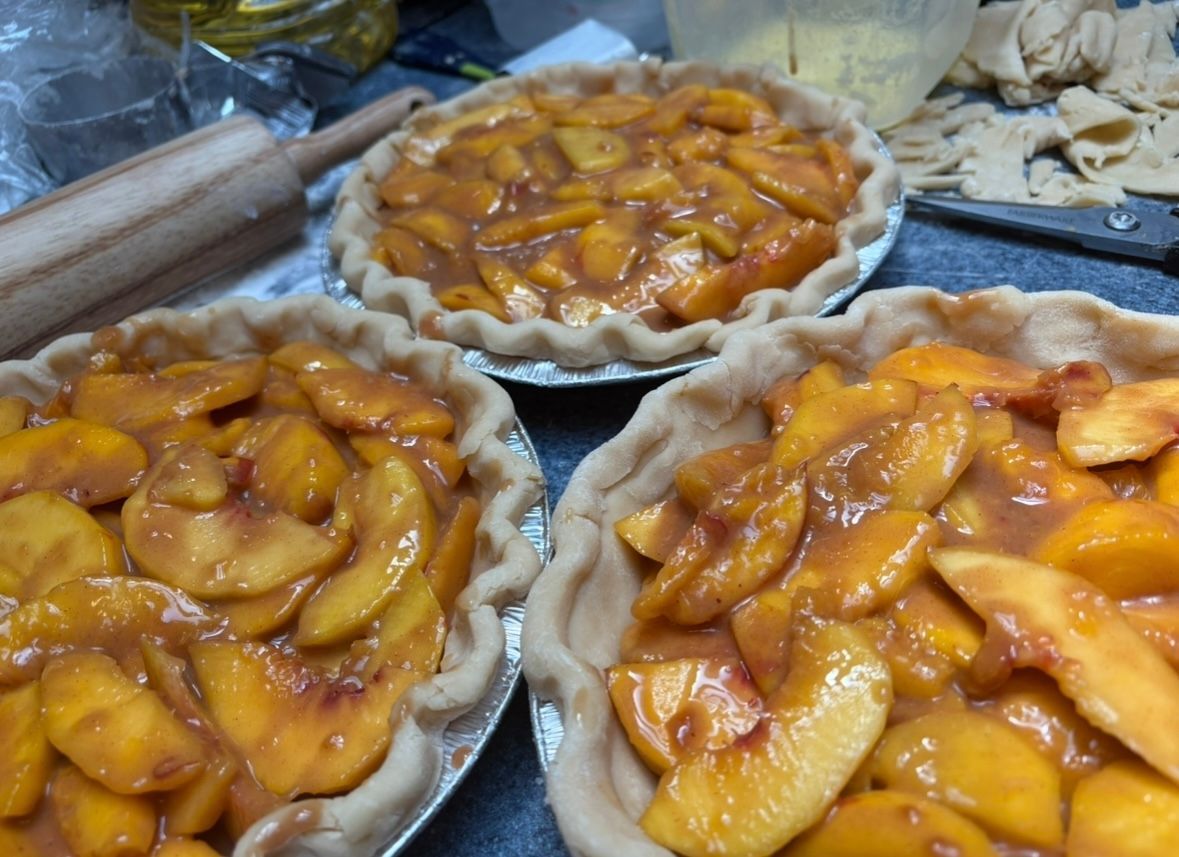 Three peach pies, golden brown, in their crusts. Base Camp Bakery Gunnison, Colorado https://share.google/AgqUzUKNzsb0ThlP5, https://www.facebook.com/BaseCampBakery1, https://www.instagram.com/basecampbakery_81230