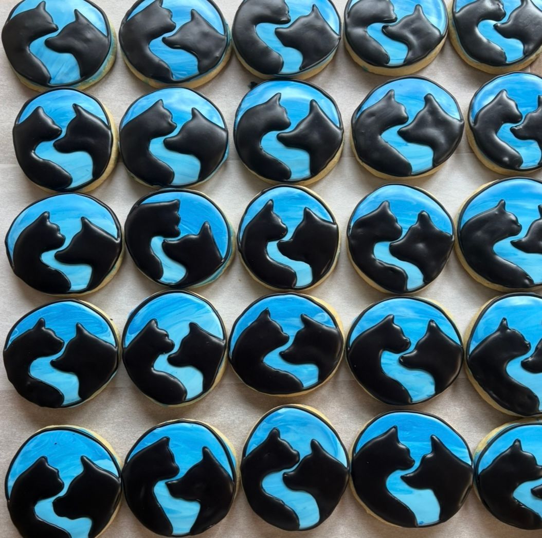 Round cookies decorated with black cat silhouettes on blue backgrounds. Base Camp Bakery Gunnison, Colorado https://share.google/AgqUzUKNzsb0ThlP5, https://www.facebook.com/BaseCampBakery1, https://www.instagram.com/basecampbakery_81230