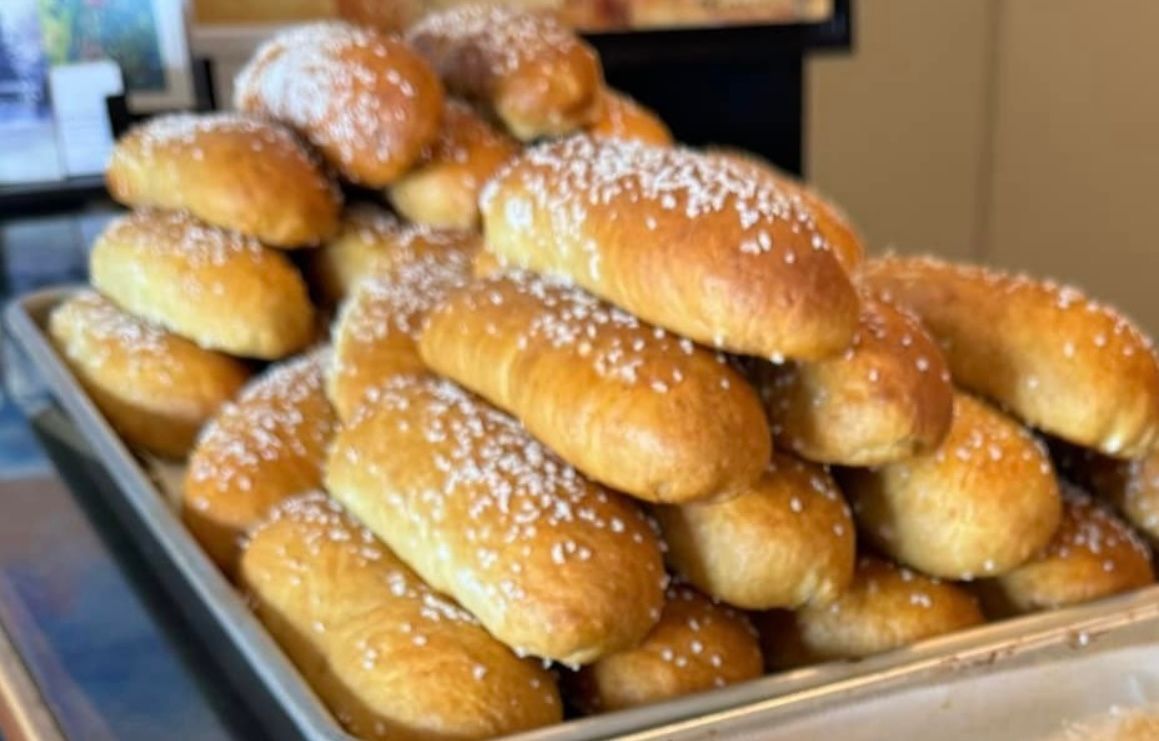 Pile of golden-brown pretzel rolls sprinkled with coarse salt on a baking sheet. Base Camp Bakery Gunnison, Colorado https://share.google/AgqUzUKNzsb0ThlP5, https://www.facebook.com/BaseCampBakery1, https://www.instagram.com/basecampbakery_81230