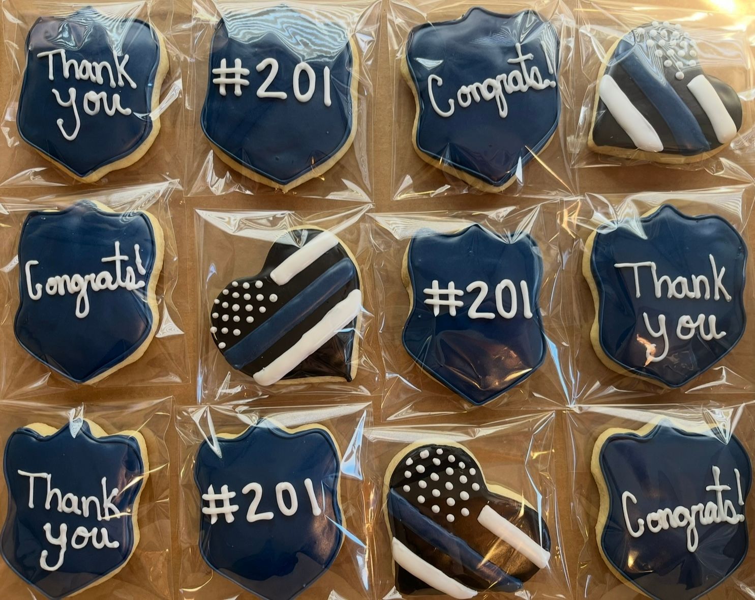Cookies decorated with blue and white frosting in police badge and heart shapes. Base Camp Bakery Gunnison, Colorado https://share.google/AgqUzUKNzsb0ThlP5, https://www.facebook.com/BaseCampBakery1, https://www.instagram.com/basecampbakery_81230