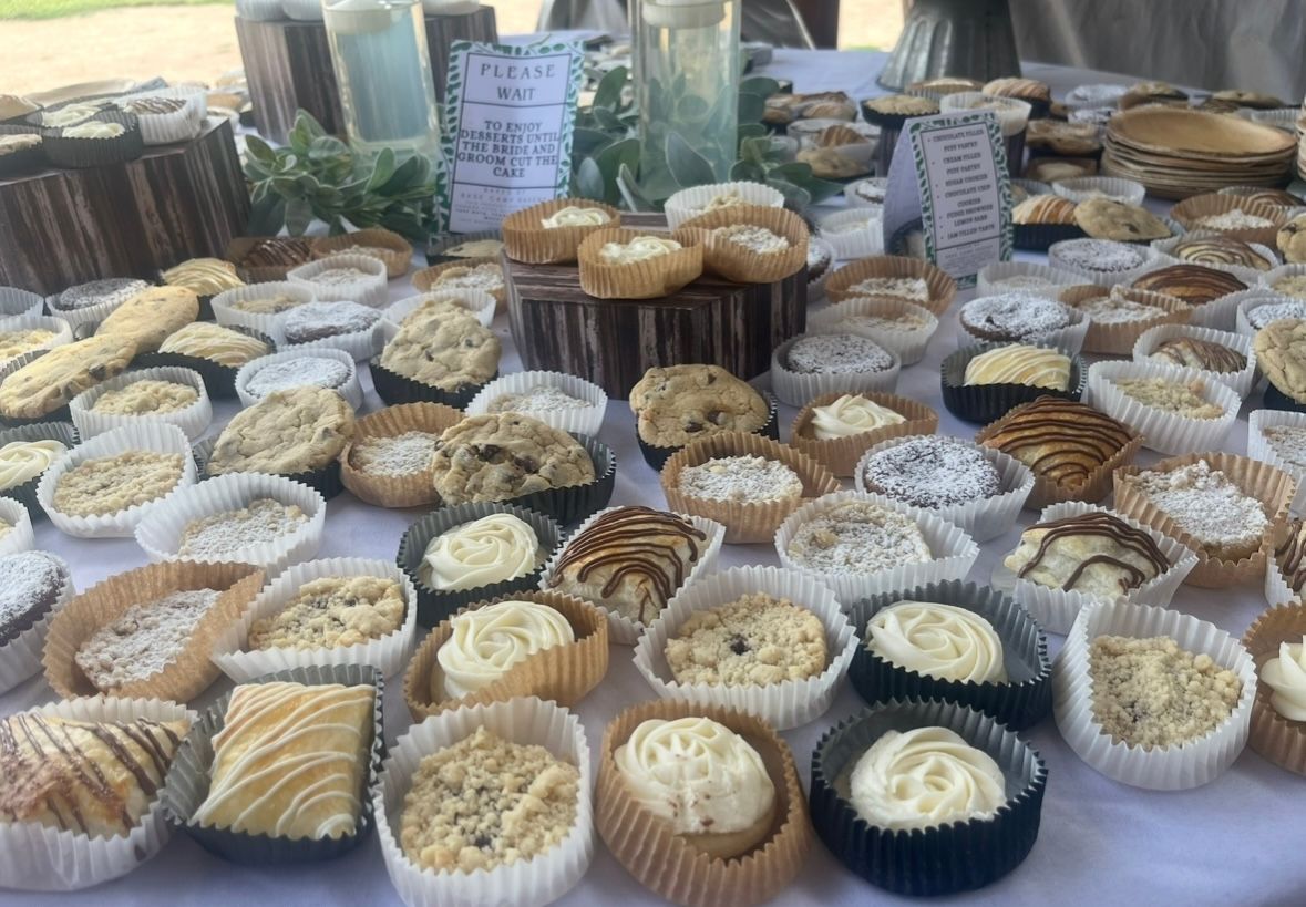 Baked goods display on a table, including cupcakes, muffins, and cookies in paper liners. Base Camp Bakery Gunnison, Colorado https://share.google/AgqUzUKNzsb0ThlP5, https://www.facebook.com/BaseCampBakery1, https://www.instagram.com/basecampbakery_81230