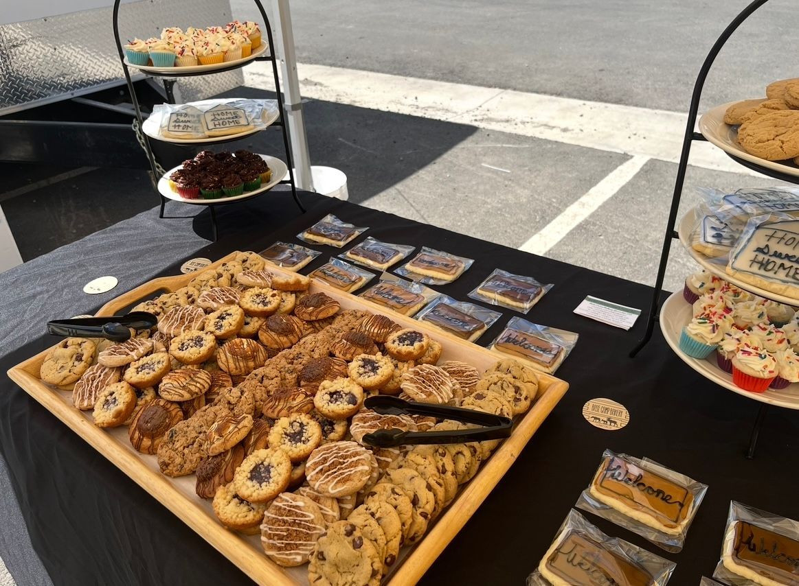 Dessert display: cookies, brownies, and cupcakes on tiered stands, black tablecloth, outdoor setting. Base Camp Bakery Gunnison, Colorado https://share.google/AgqUzUKNzsb0ThlP5, https://www.facebook.com/BaseCampBakery1, https://www.instagram.com/basecampbakery_81230