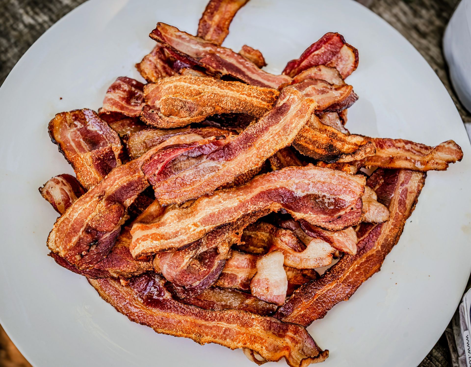 Crispy bacon strips piled on a white plate.