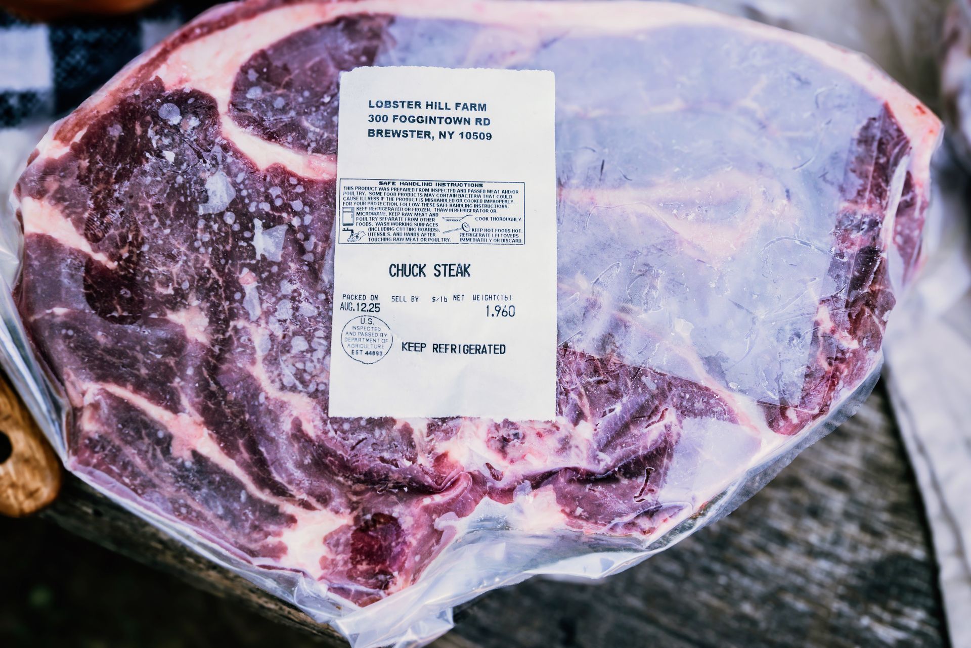 Raw chuck steak in clear plastic wrap, with a product label.