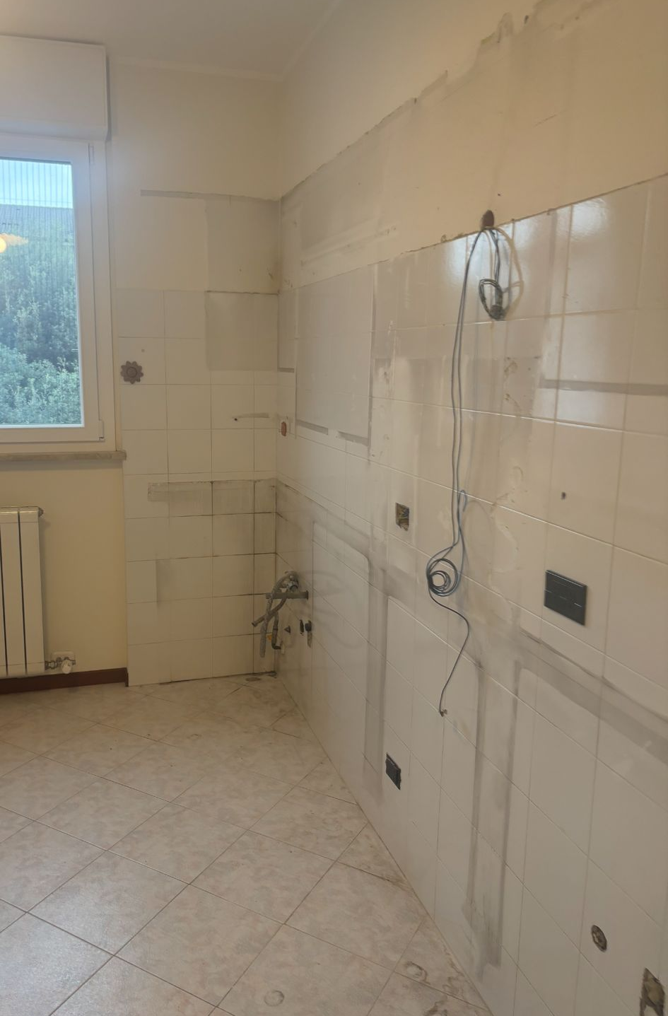 Stanza con mobili smontati e finestra aperta, alcuni oggetti sono ammucchiati contro un muro.