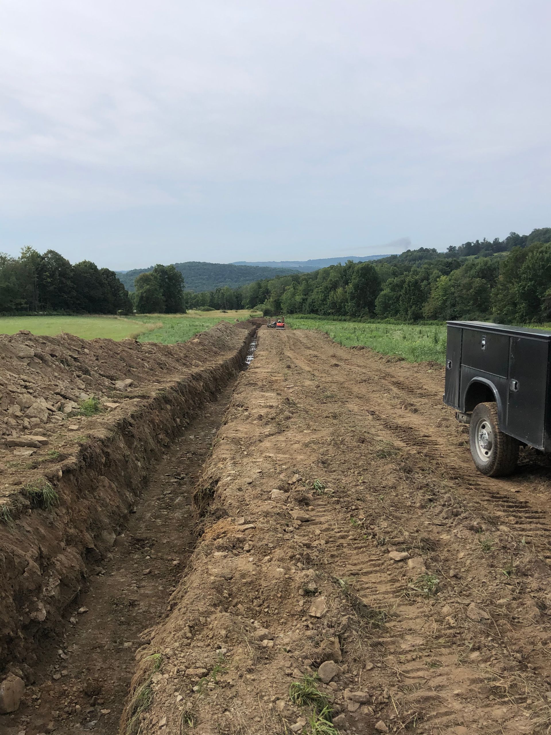 A Truck is Driving Down the Road Next to a Field