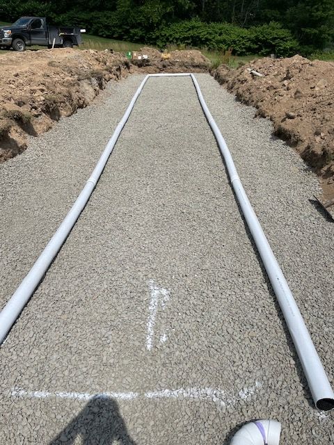 A Row of White Pipes Are Lined Up on a Gravel Road