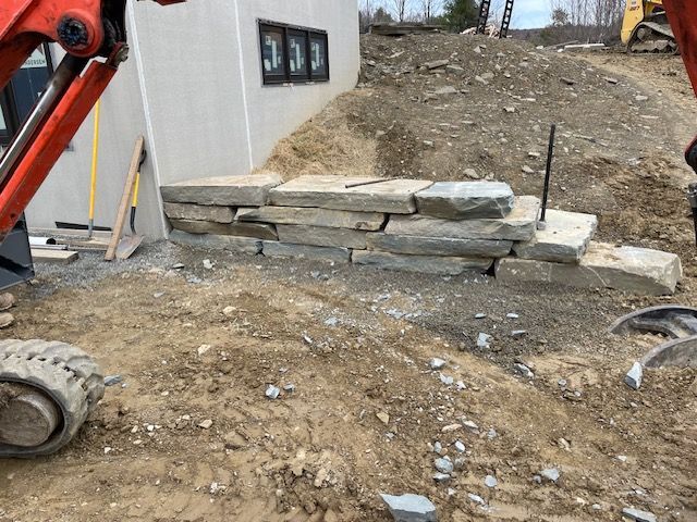 A Large Rock Wall is Being Built in Front of a House