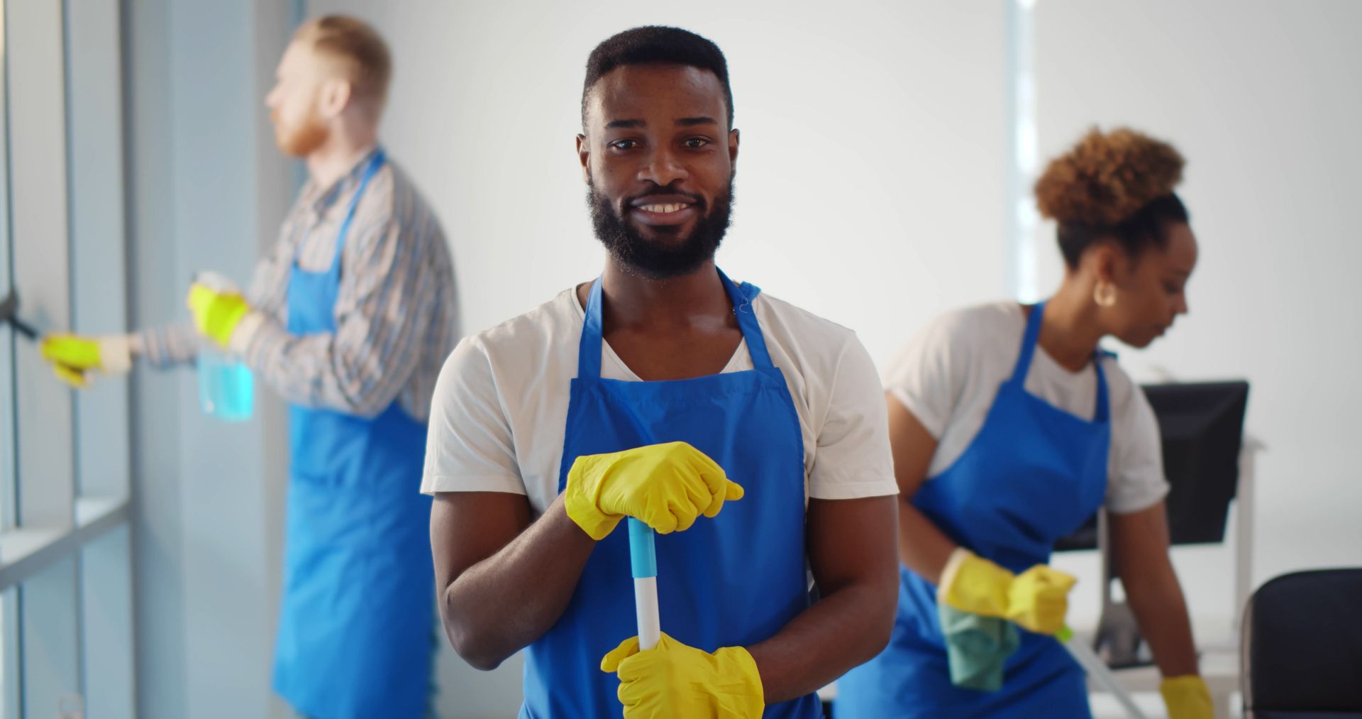 A man is holding a mop in front of a group of cleaners.