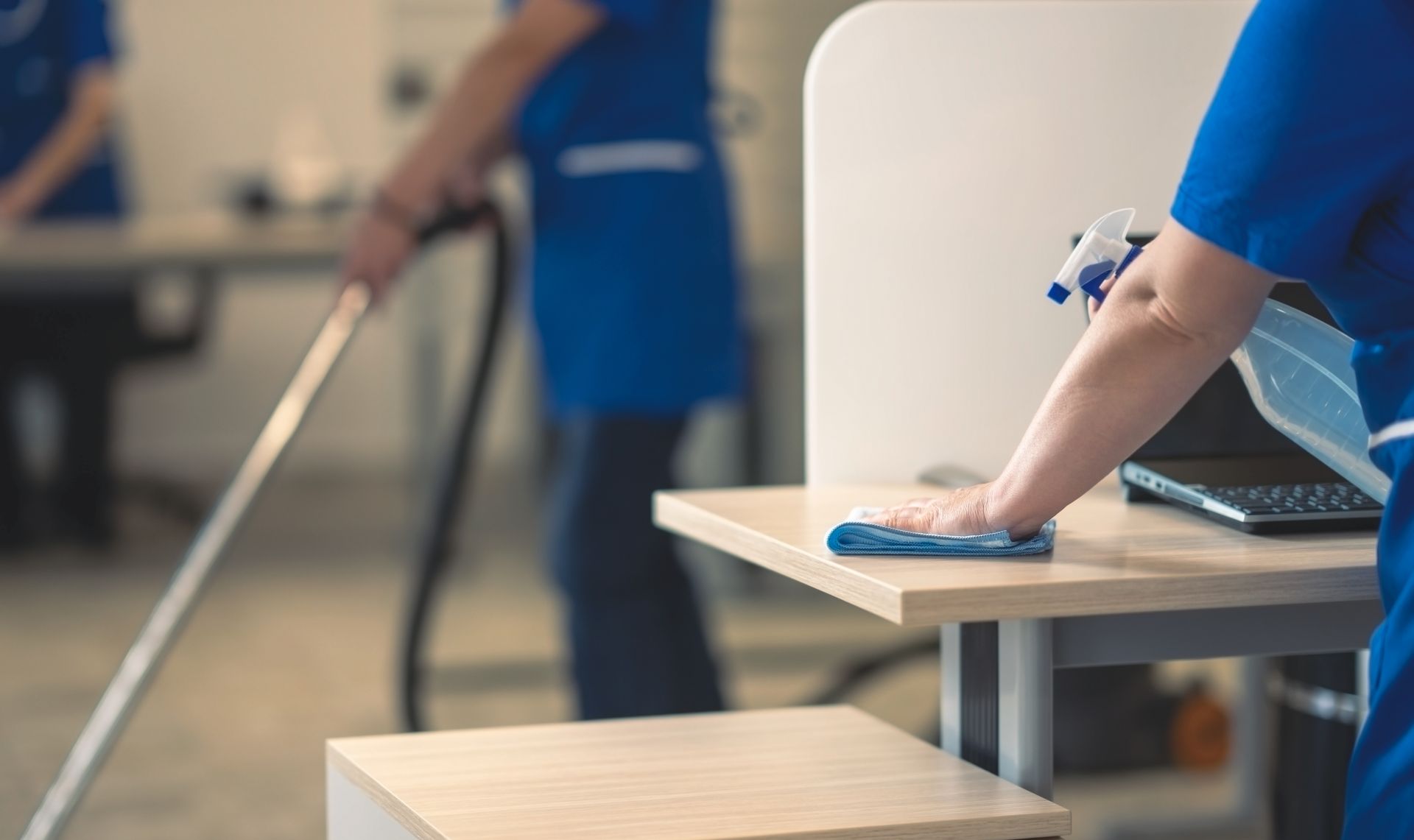 A woman is cleaning a desk with a cloth in an office.