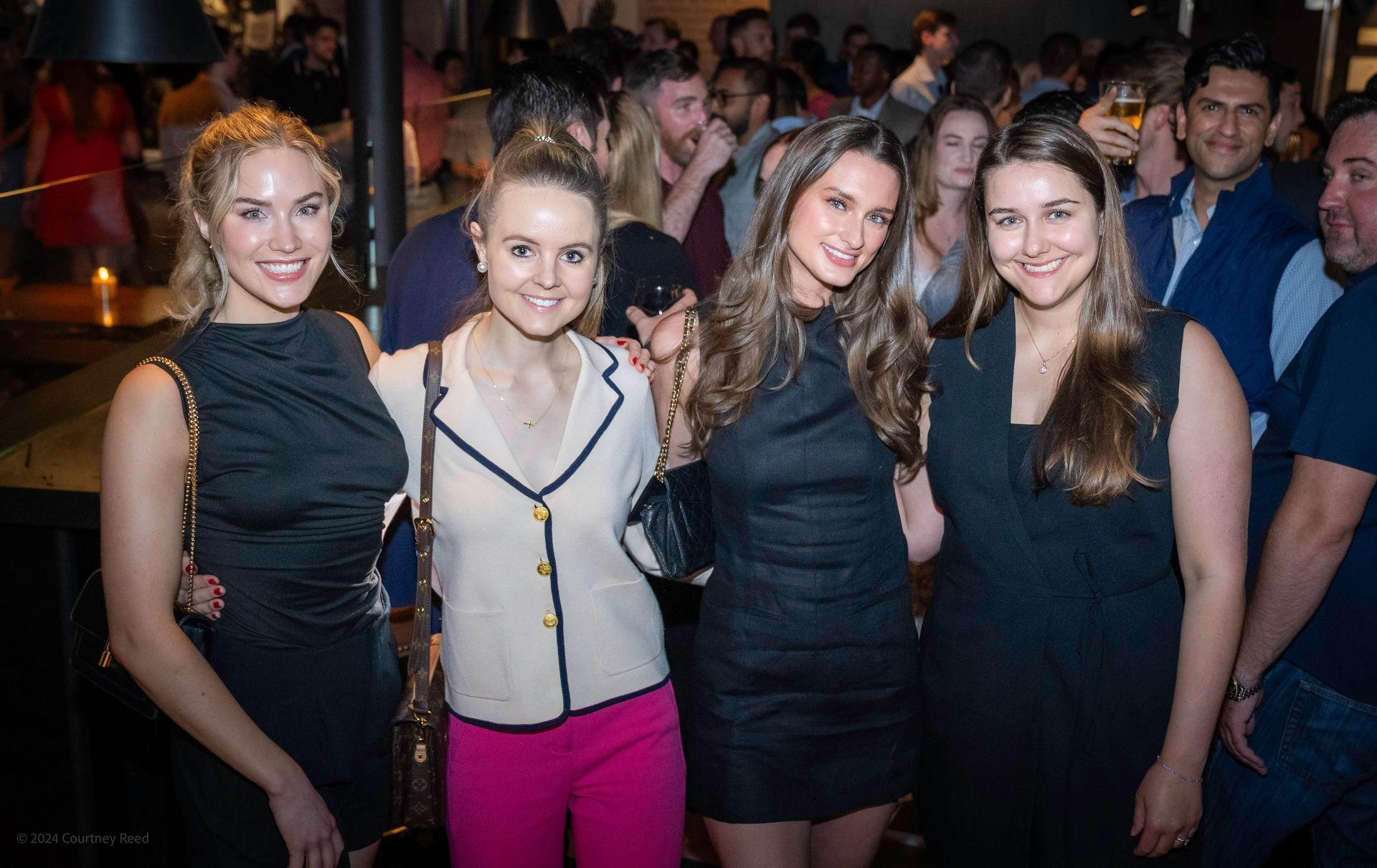 A group of women are posing for a picture in a crowded room.