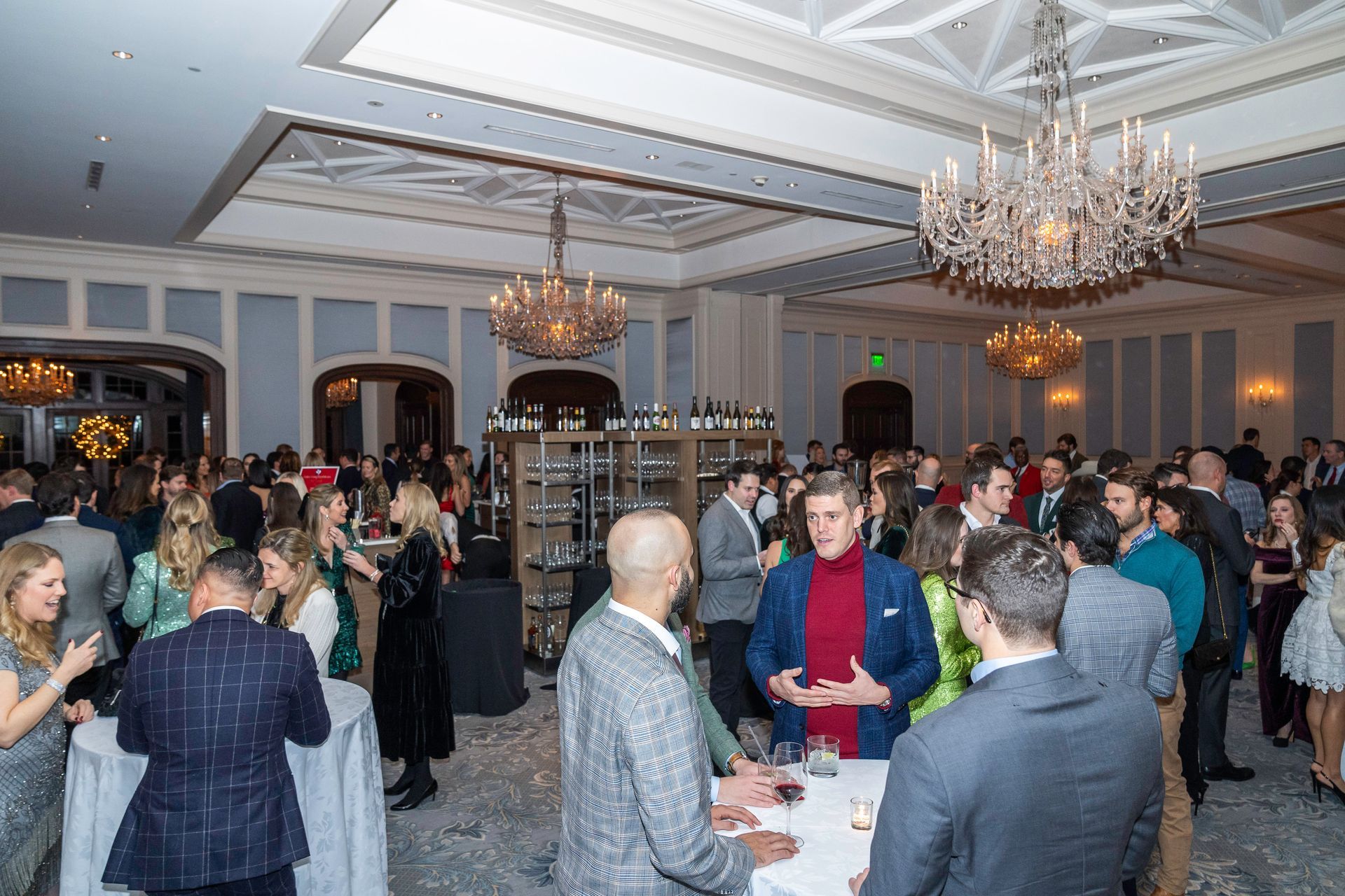 A large group of people are standing around tables in a large room.