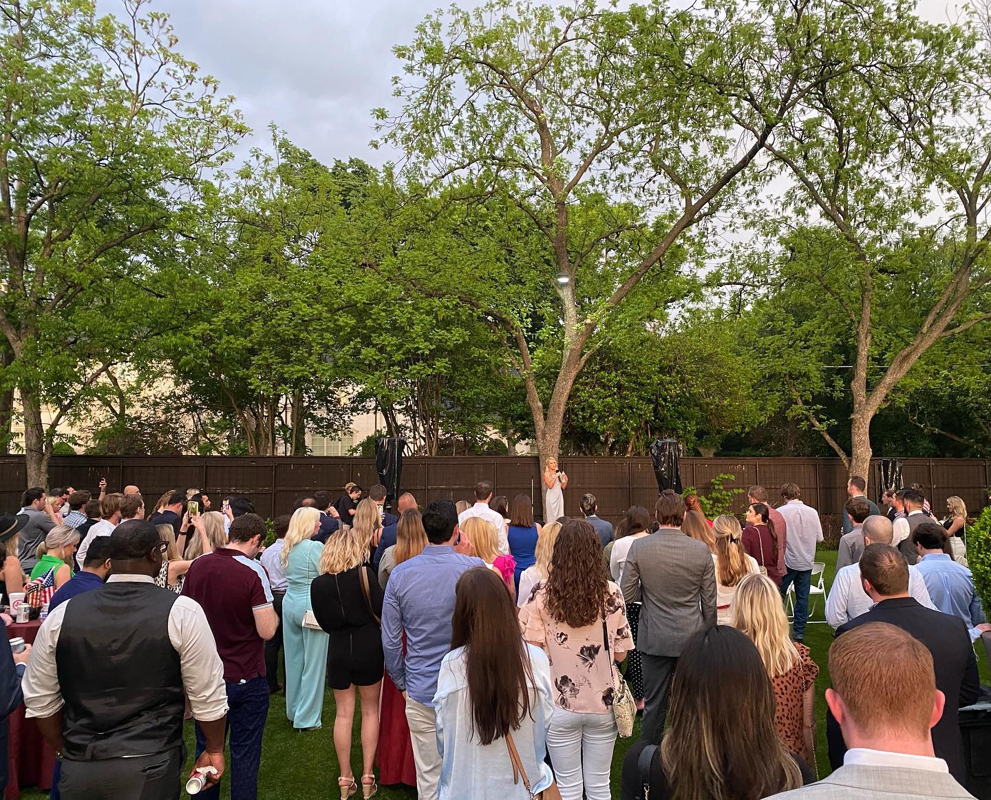 A large group of people are standing in a park.