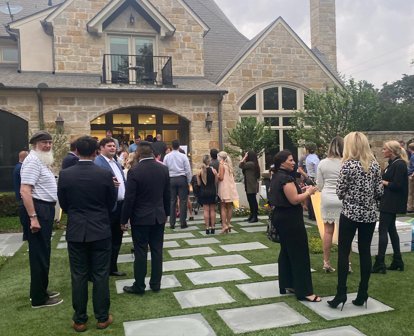 A group of people are standing in front of a large stone house.