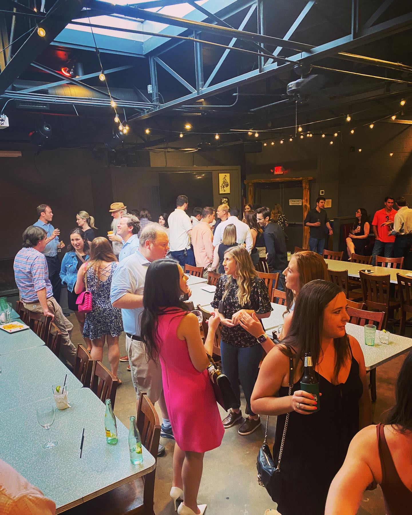 A group of people are standing around tables in a restaurant