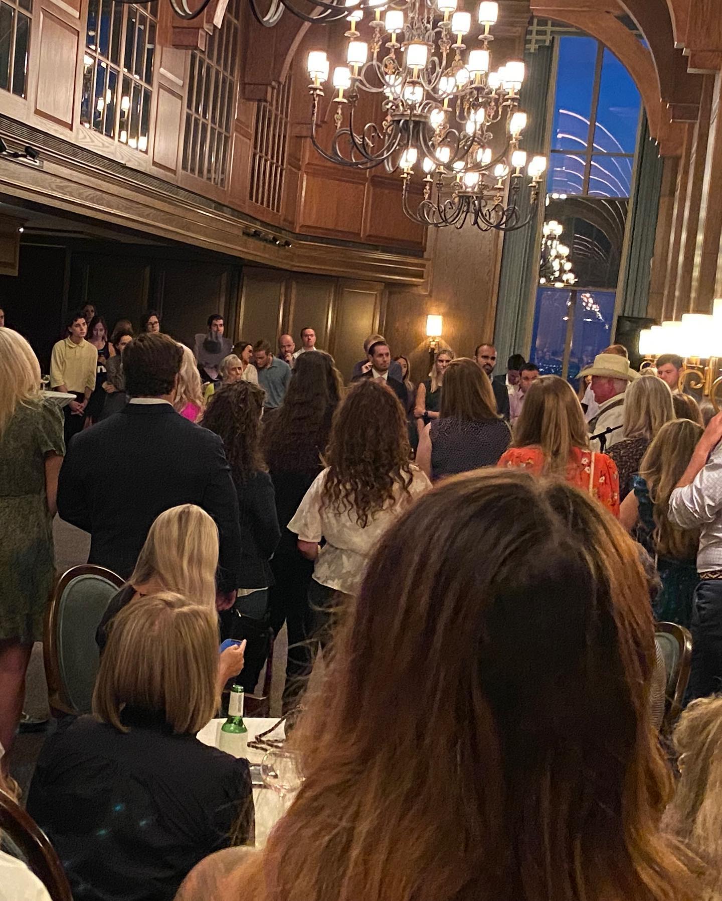 A large group of people are sitting at tables in a large room.