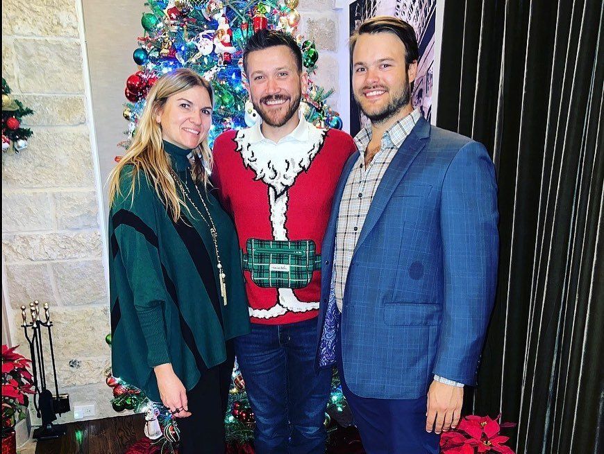 Three people are posing for a picture in front of a christmas tree.