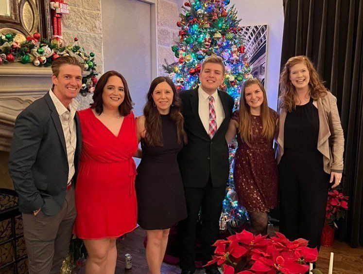 A group of people are posing for a picture in front of a christmas tree.