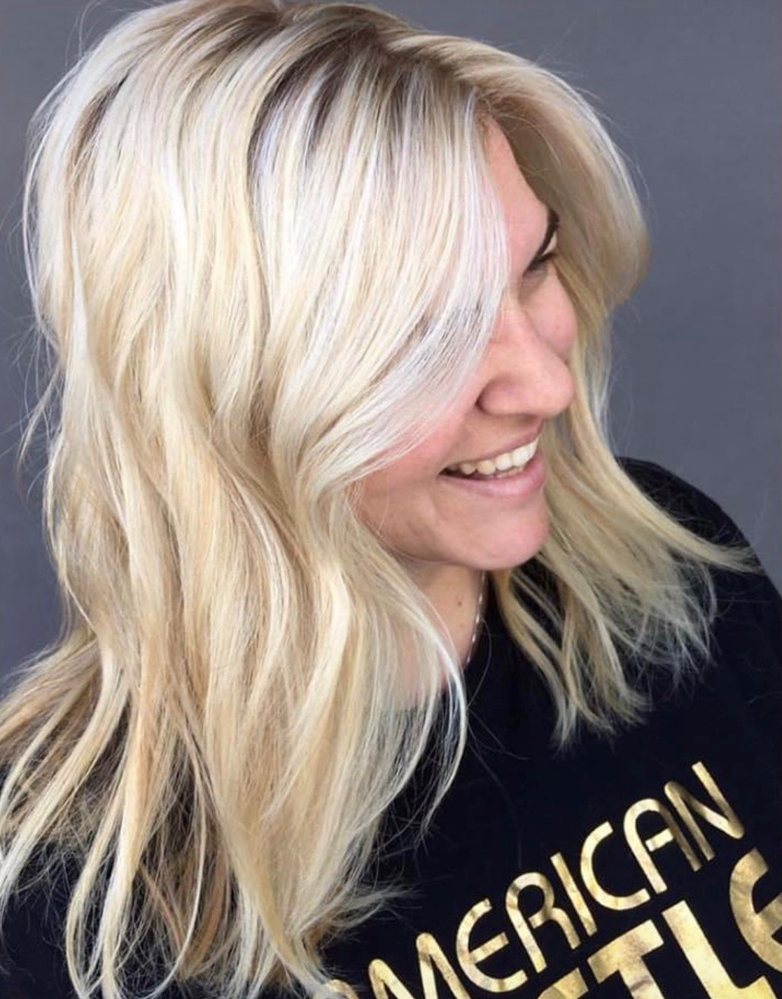 A woman with blonde hair is wearing a black shirt with the word american on it.