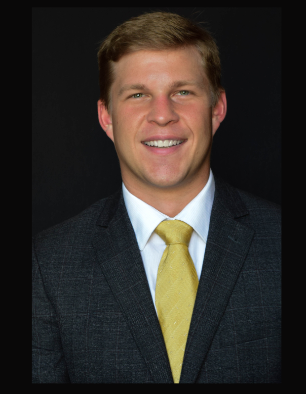 A man in a suit and tie is smiling for the camera
