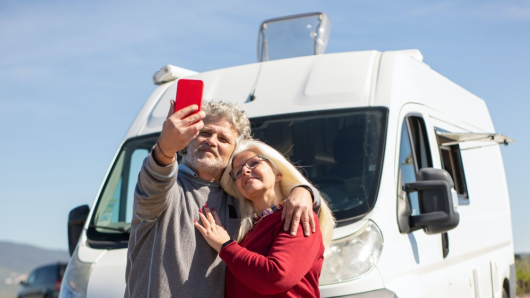 Un uomo e una donna si scattano un selfie davanti a un camper.