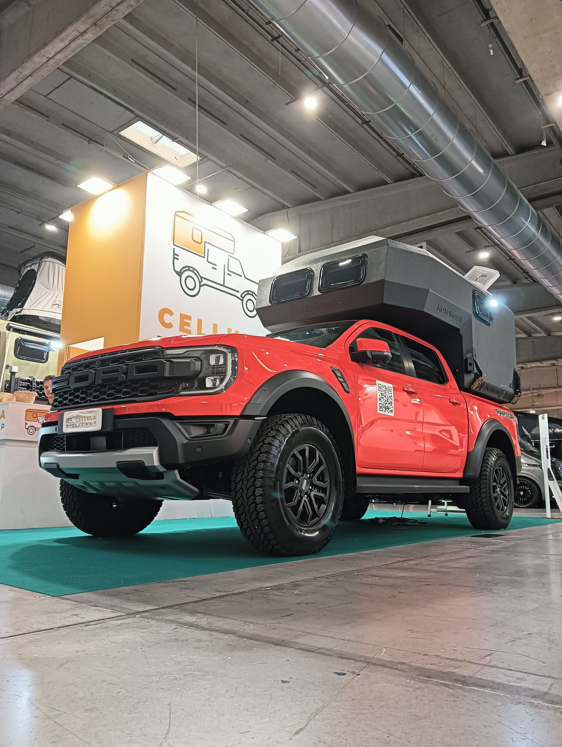 Un camion rosso è parcheggiato in una stanza durante una mostra di automobili.