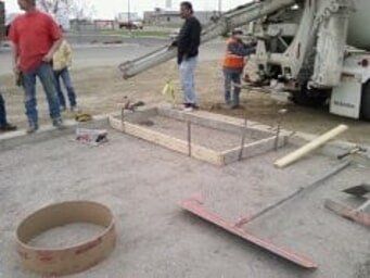 A group of construction workers are working on a concrete driveway.