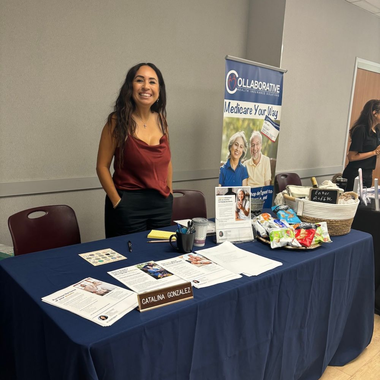 Woman at a table with marketing materials; a sign reads