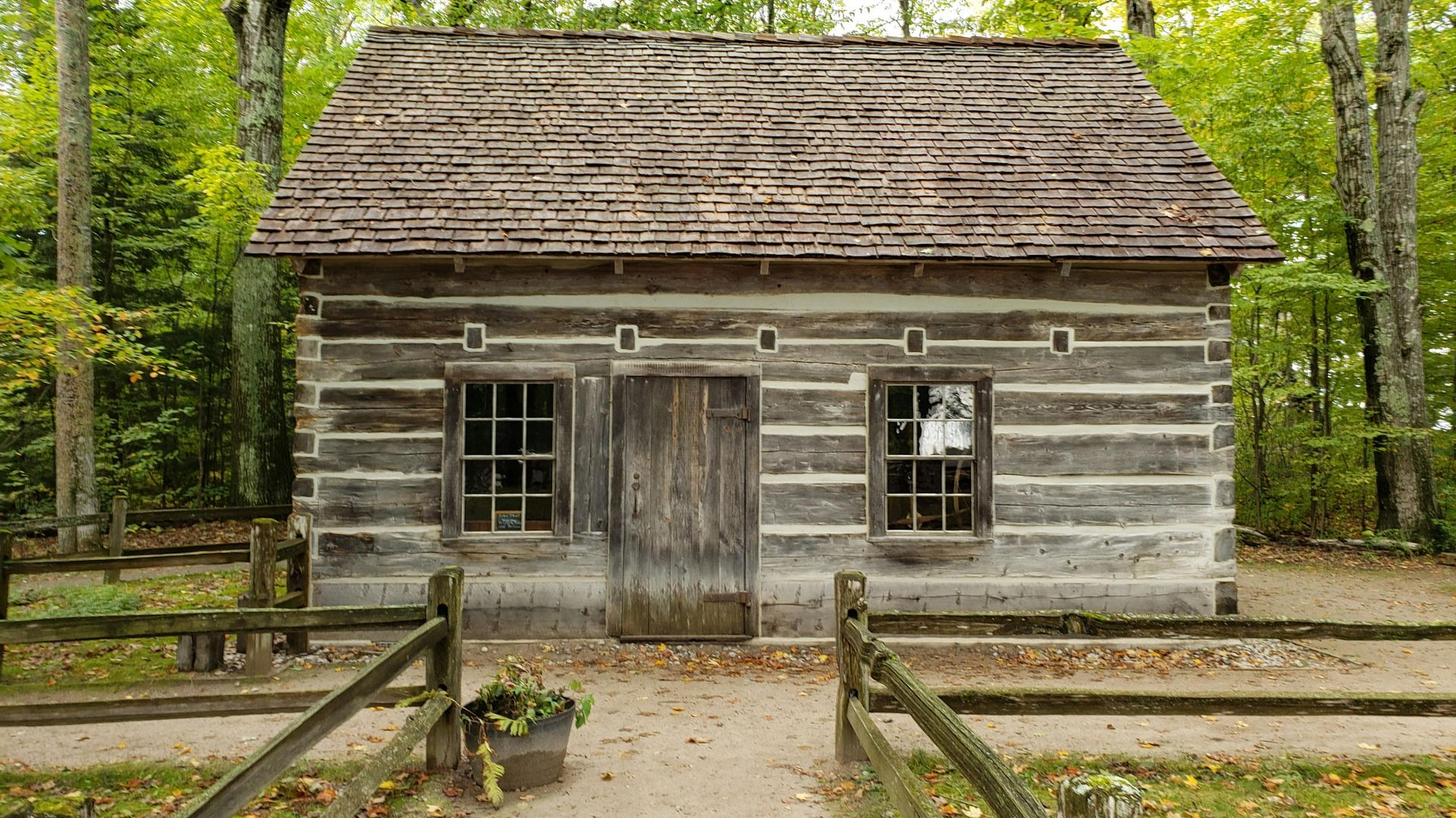 Weathered log cabin with a wooden door and windows in a wooded forest setting
