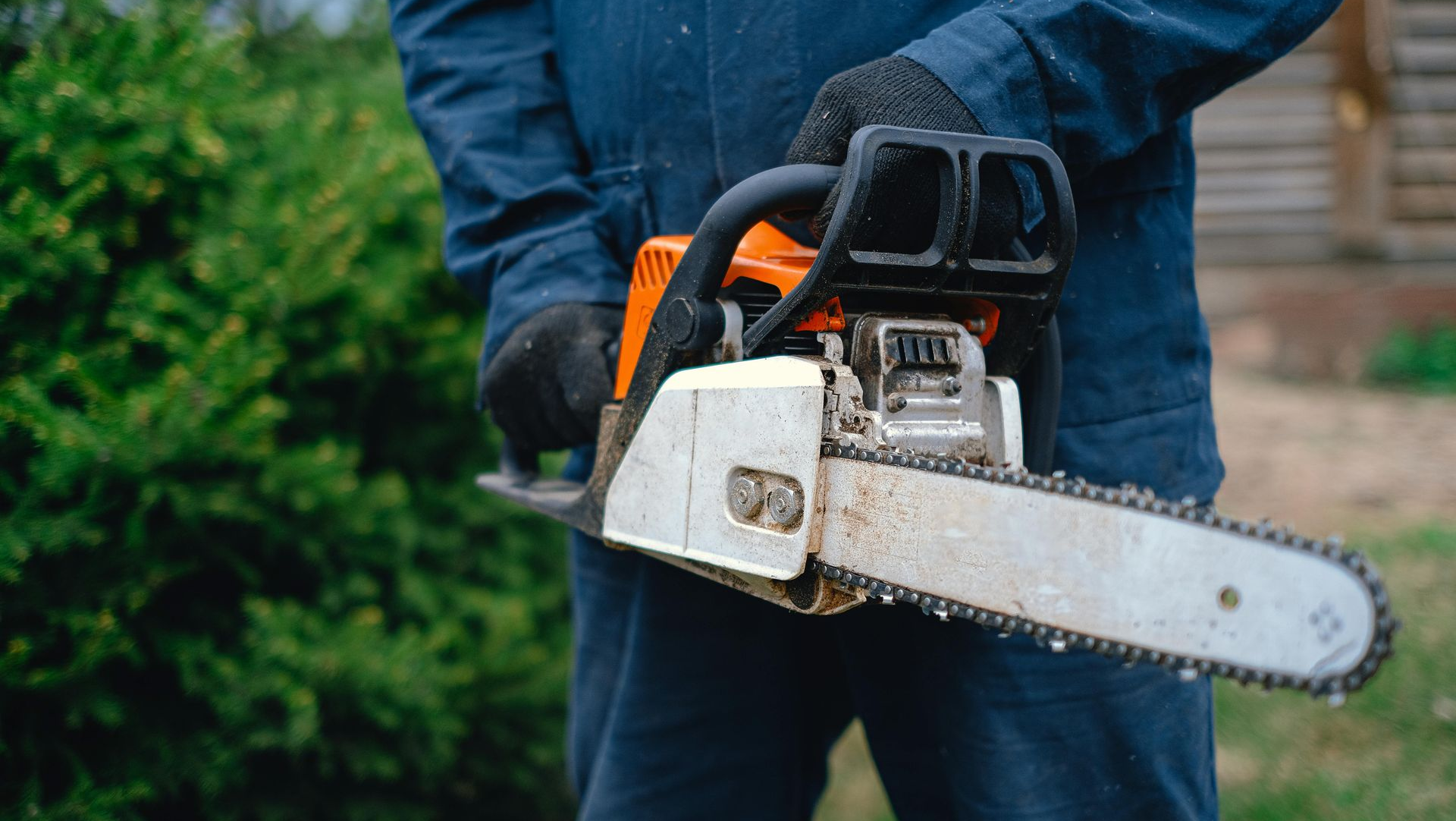 Person holding a white chainsaw outdoors in a green yard