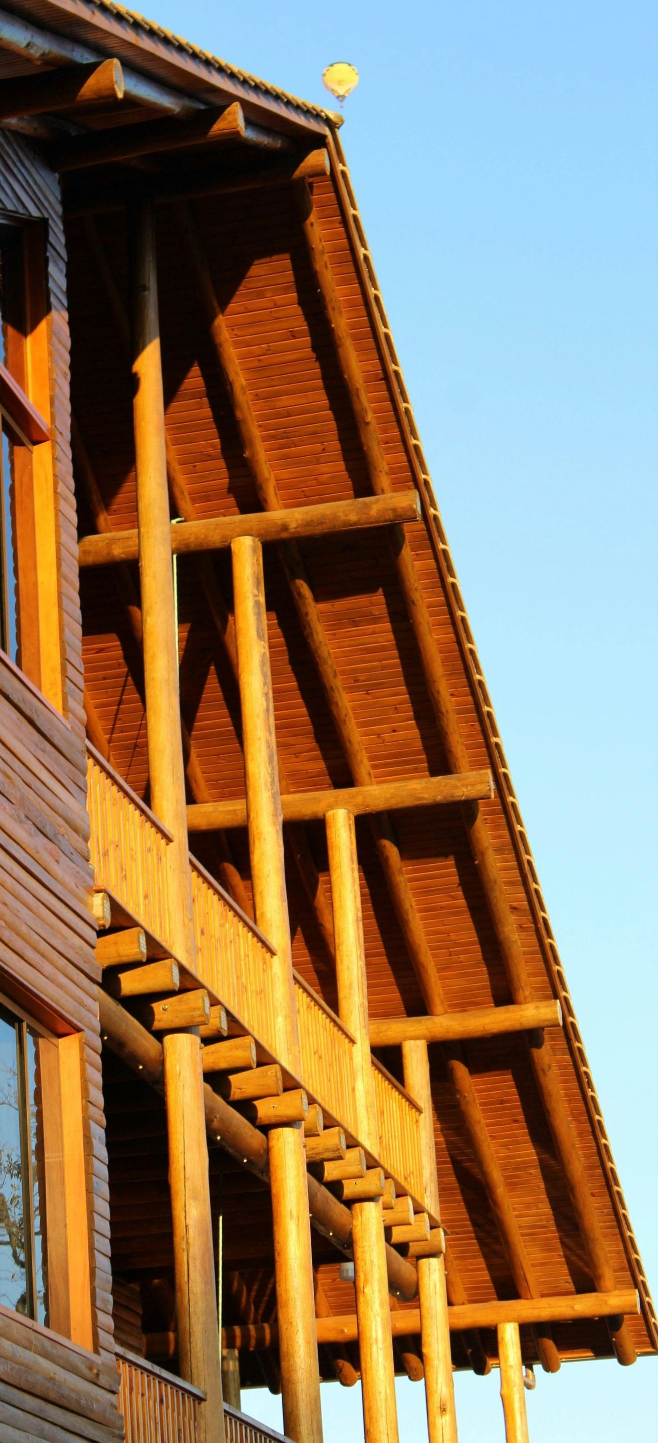 Wooden building exterior with slanted roof and vertical beams against a blue sky