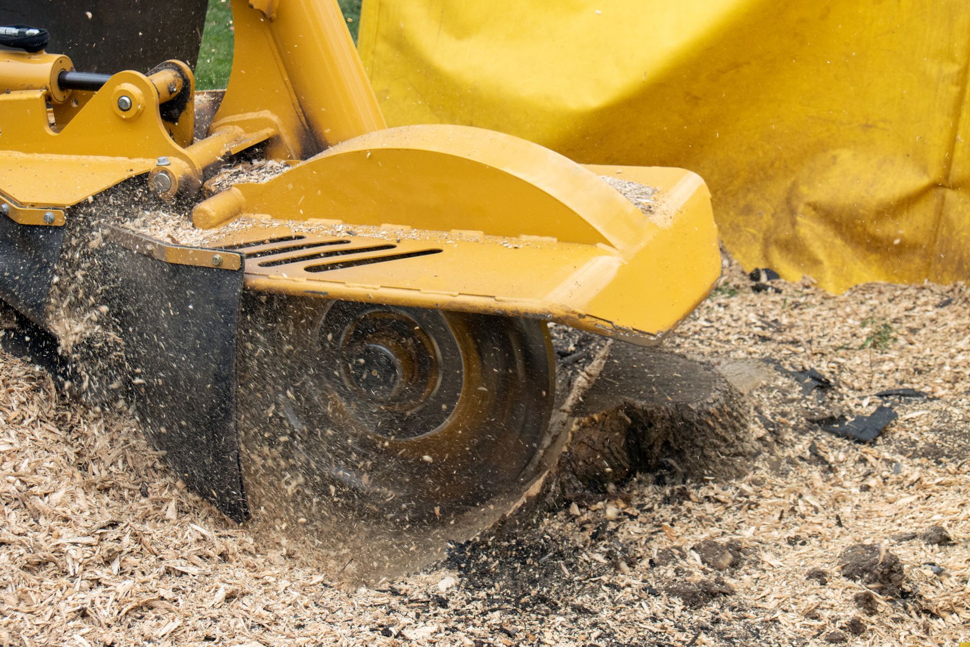 Yellow construction vehicle blade cutting through muddy ground, kicking up dirt and water Yellow construction vehicle blade cutting through muddy ground, kicking up dirt and water