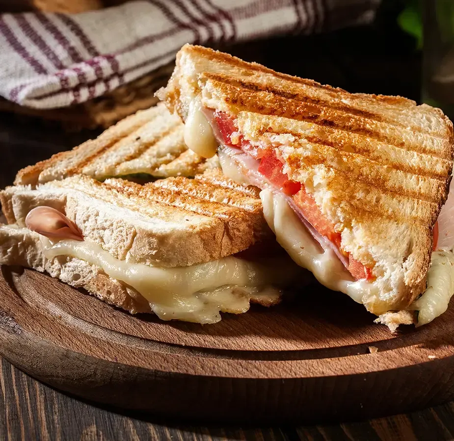 A plate of hot off the press paninis on a wooden plate.