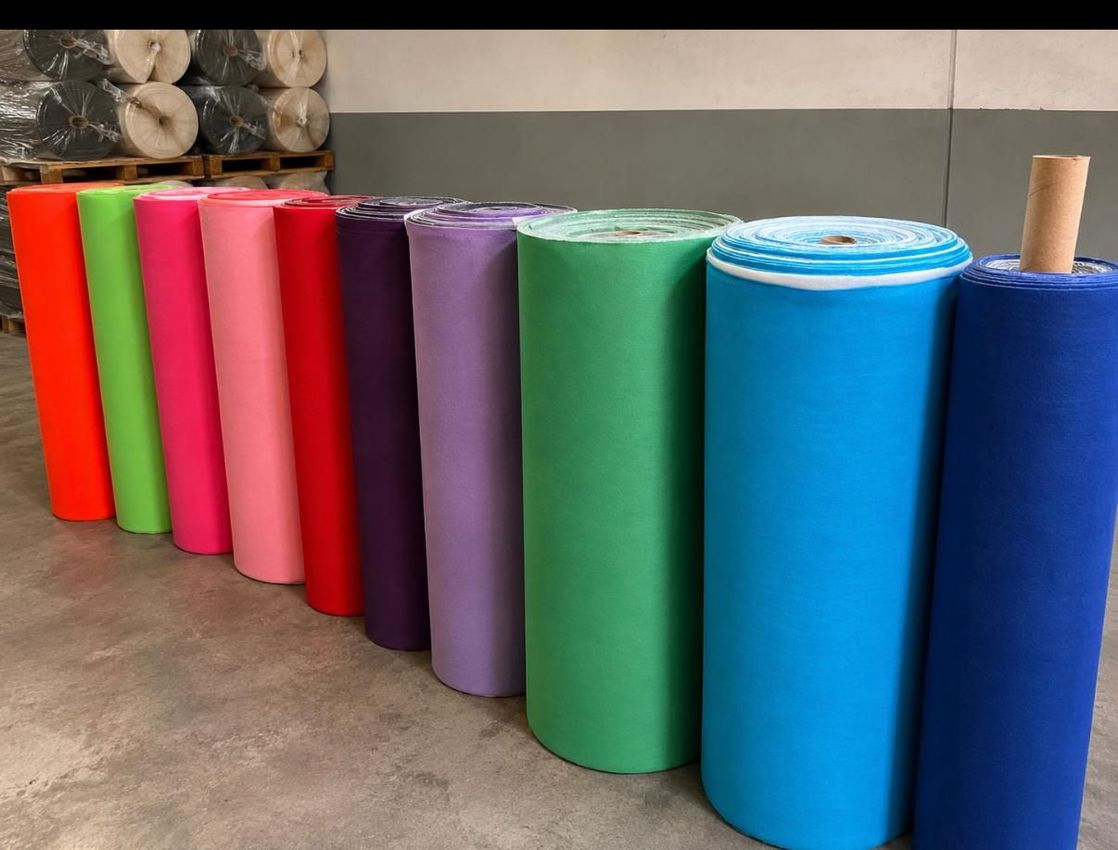 Hilera de coloridas esterillas de yoga enrolladas o rollos de espuma colocados verticalmente sobre un suelo de hormigón.