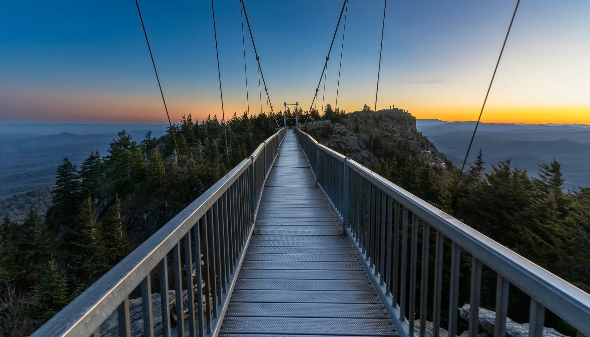 A bridge over a body of water with a sunset in the background.
