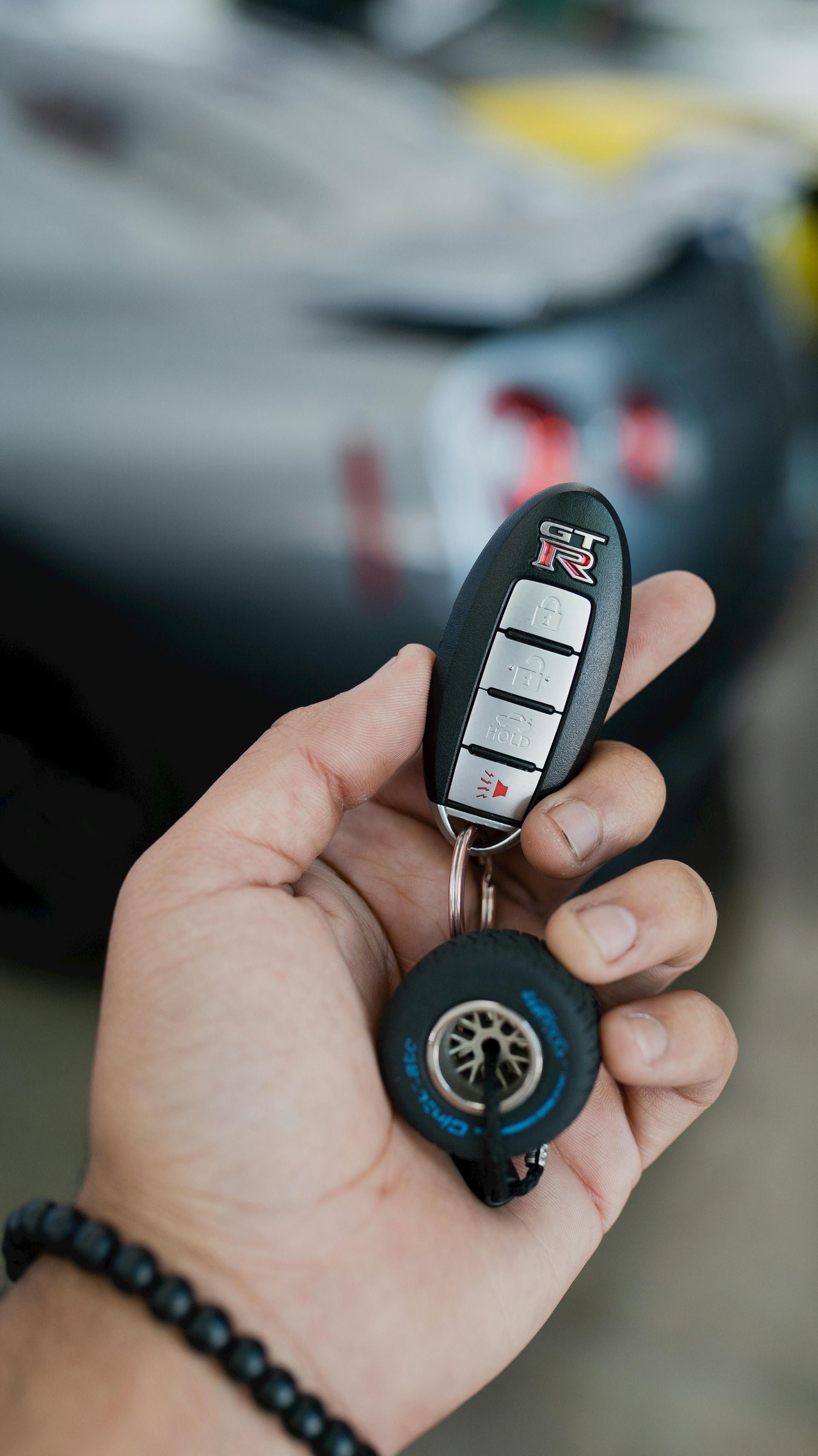 A person is holding a car key in their hand in front of a car.