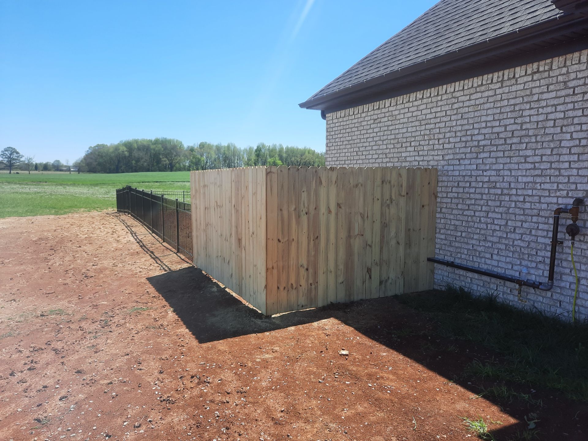 A wooden fence is sitting next to a white brick building.
