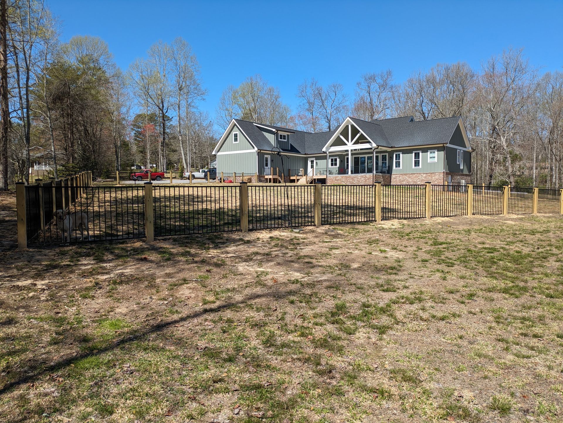A large house is behind a wooden fence in a field.